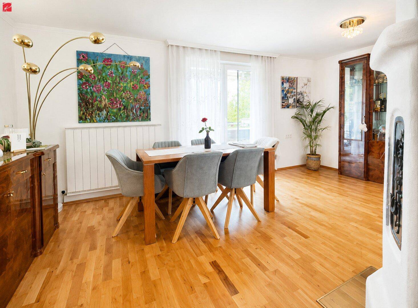 Gemütlicher Essbereich mit Holzboden, großem Esstisch und farbenfroher Wandkunst für eine lebendige Atmosphäre.