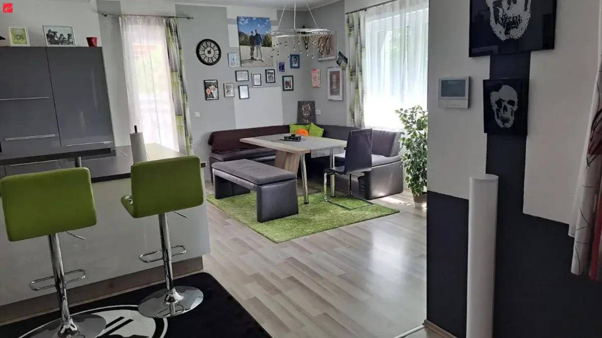 Gemütlicher Wohn-Essbereich mit Eckbank, Esstisch und Blick auf die offene Küche, hell durch große Fenster.