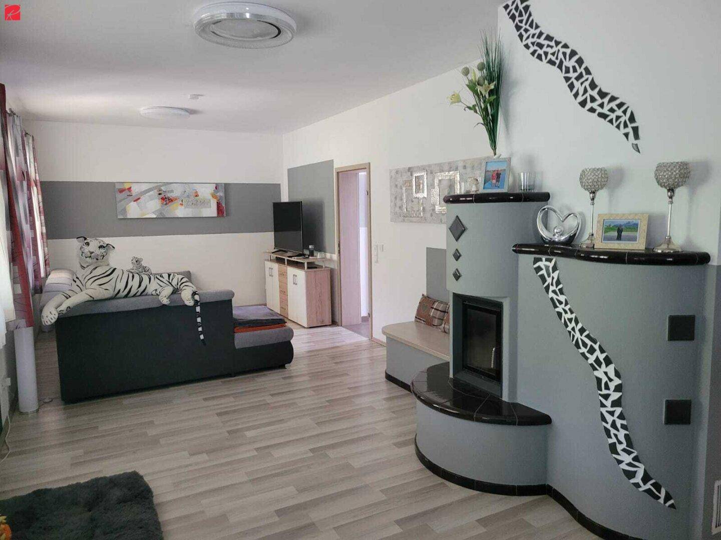 Helles Wohnzimmer mit modernem Kachelofen, Sofa und dekorativen Wandelementen.