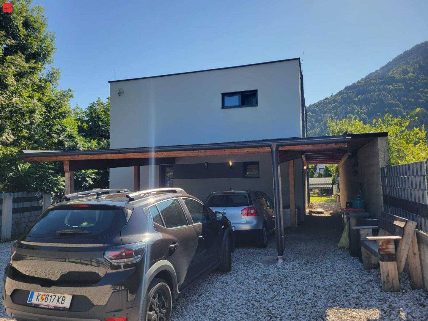 Moderne Hausfassade mit Carport für zwei Fahrzeuge und Bergblick.