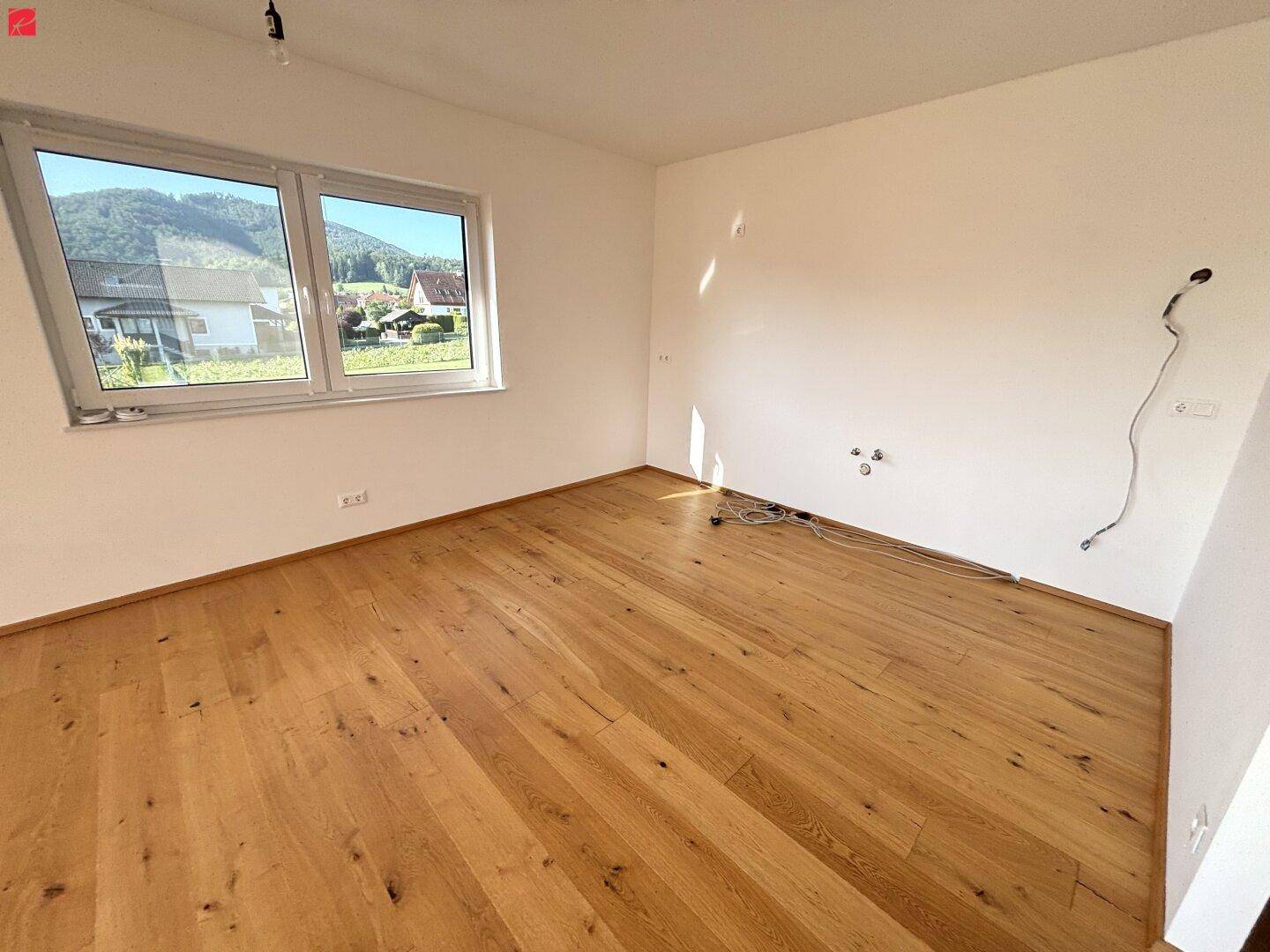 Lichtdurchflutetes Zimmer mit Holzboden und Blick ins Grüne, ideal als Schlaf- oder Arbeitszimmer.