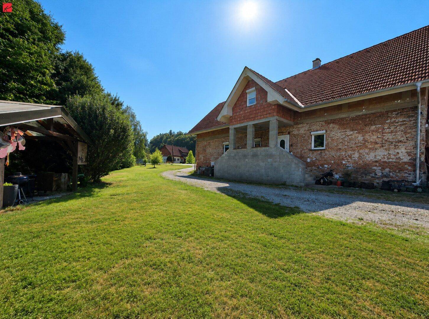 Sonniges Grundstück mit großem Rasenbereich und einem Backsteinhaus im ländlichen Stil.