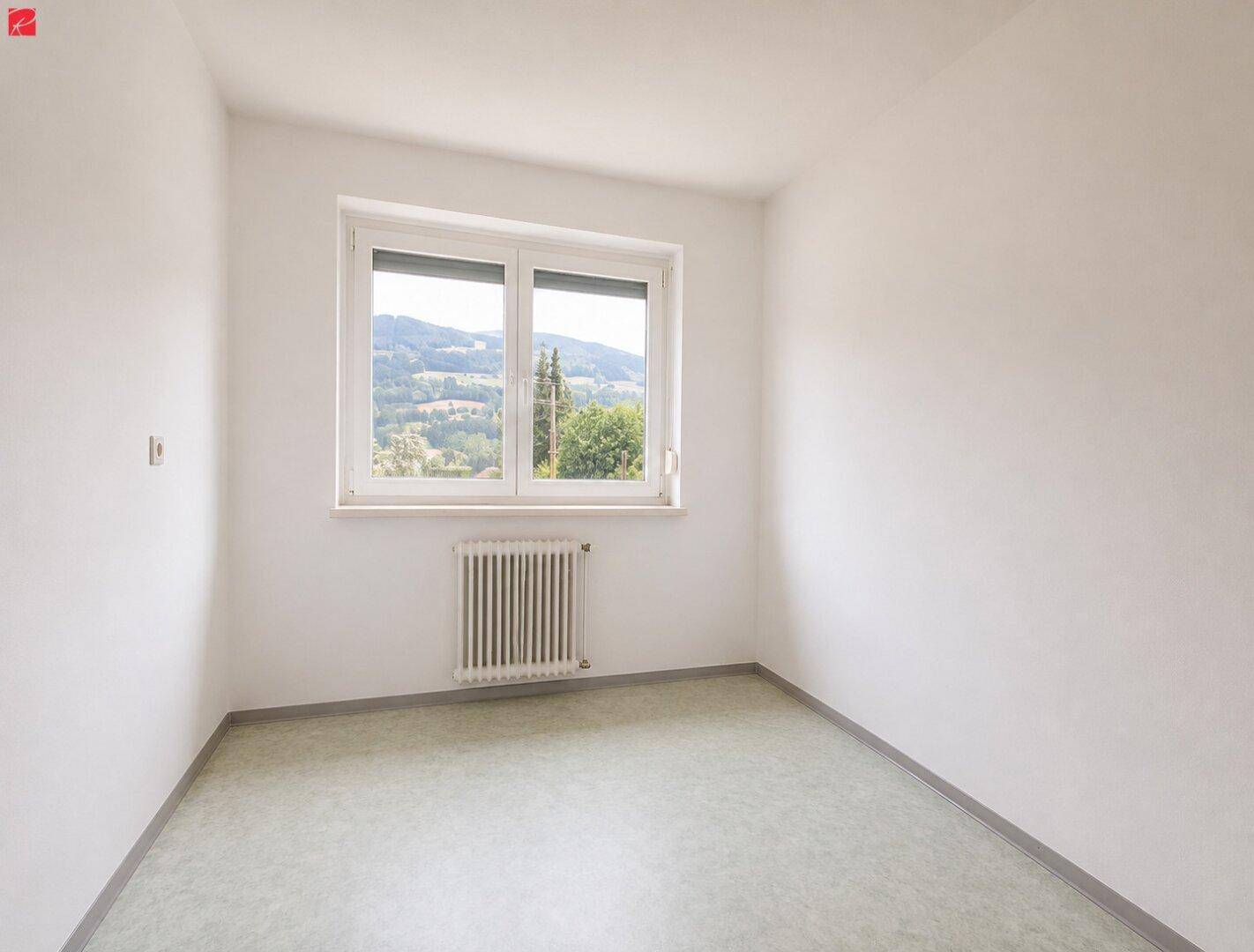 Helles Schlafzimmer mit Blick auf die umliegende Hügellandschaft und einfachem Bodenbelag.