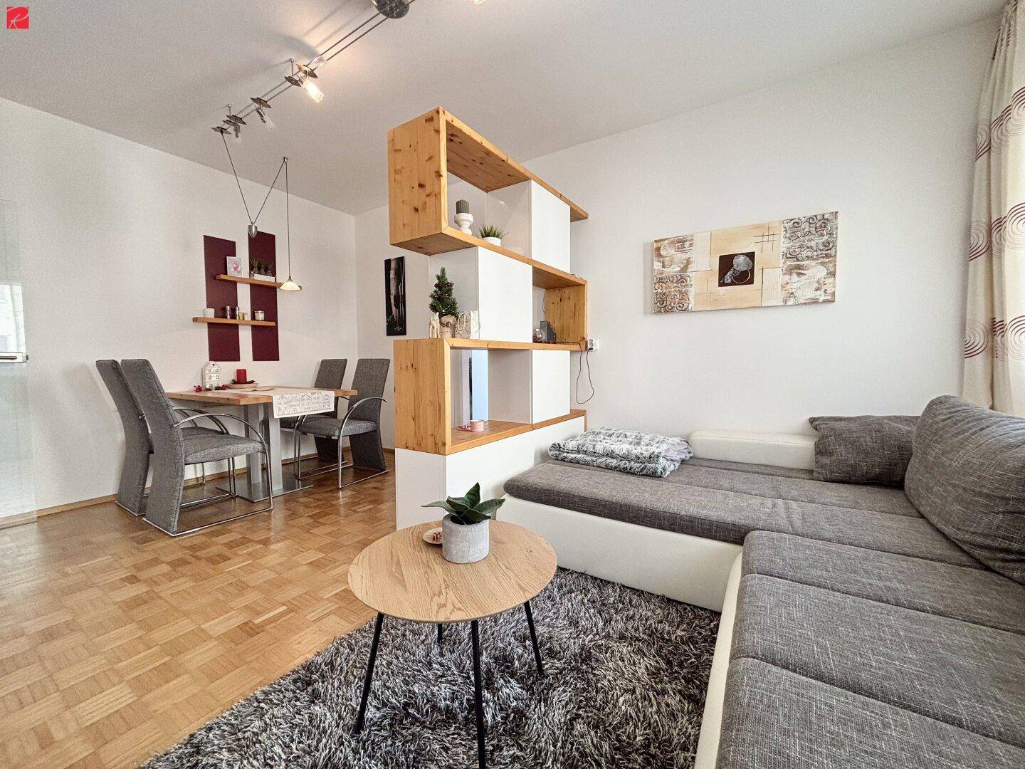 Offener Wohn- und Essbereich mit Parkettboden, Ecksofa und modernem Esstisch.
