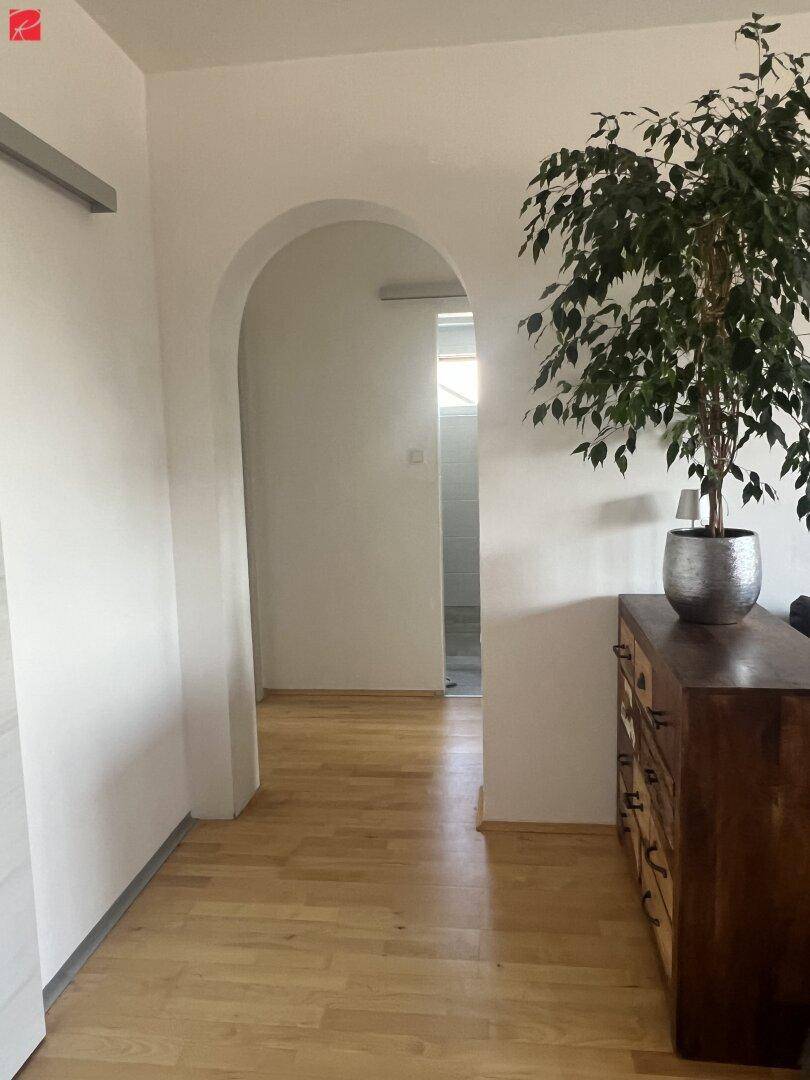 Heller Flur mit Holzboden und einem dekorativen Bogen, der zu weiteren Räumen führt.