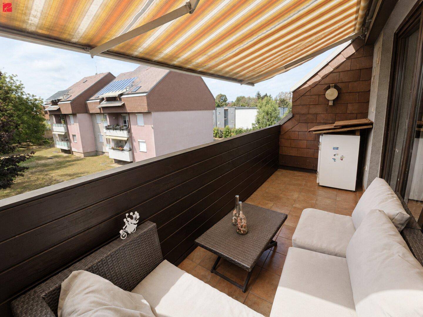 Gemütlicher Balkon mit Markise, Sitzgelegenheiten und Blick ins Grüne.