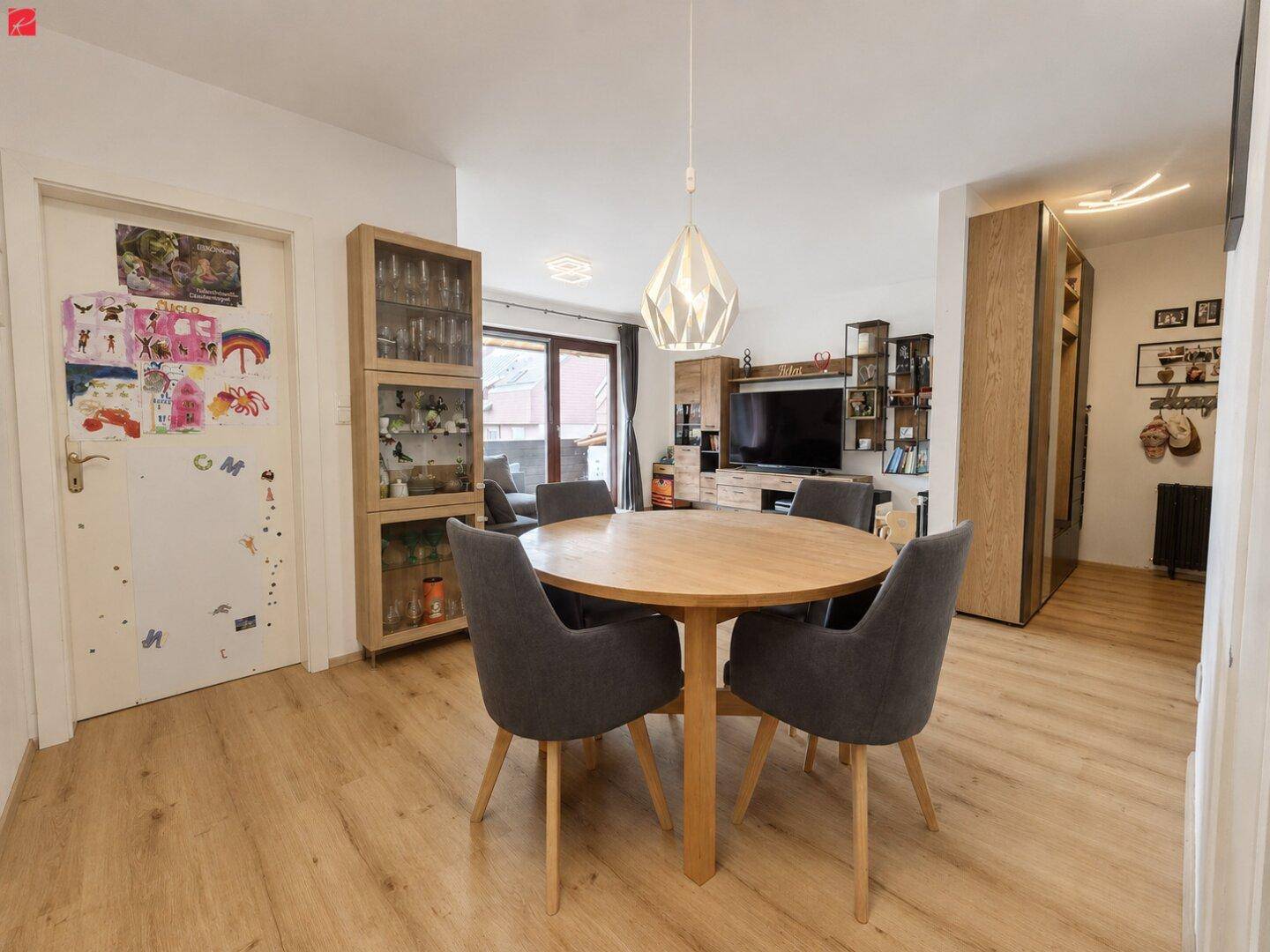 Heller Essbereich mit Holztisch und Stühlen, offen zum Wohnzimmer mit Balkonzugang.