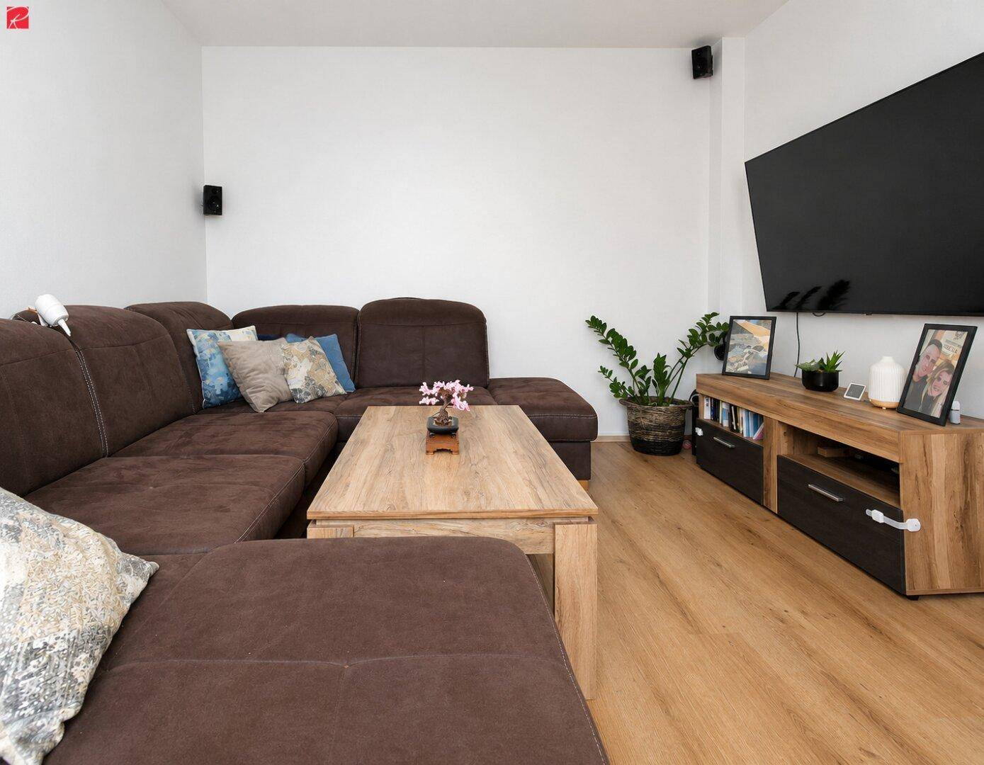 Gemütliches Wohnzimmer mit großem Ecksofa, Couchtisch und modernem Unterhaltungssystem.