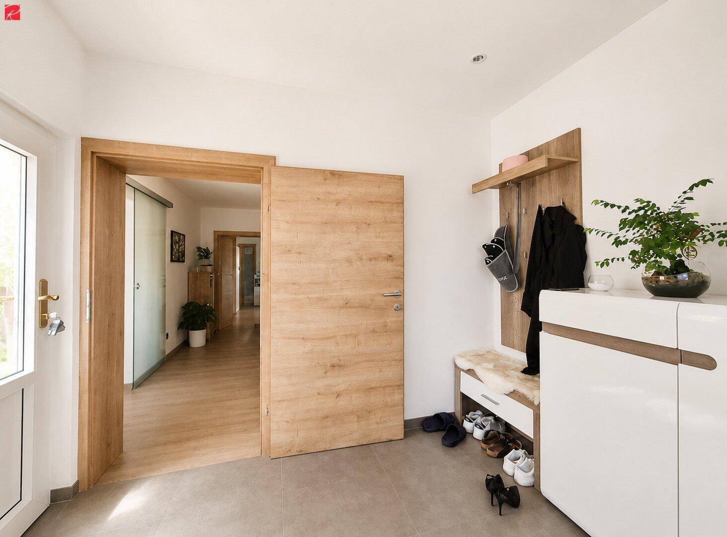 Heller Eingangsbereich mit Garderobe, Schuhablage und Zugang zu weiteren Räumen.