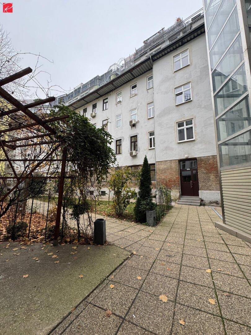 Außenansicht eines Gebäudes mit begrüntem Innenhof und externem Glasaufzug.