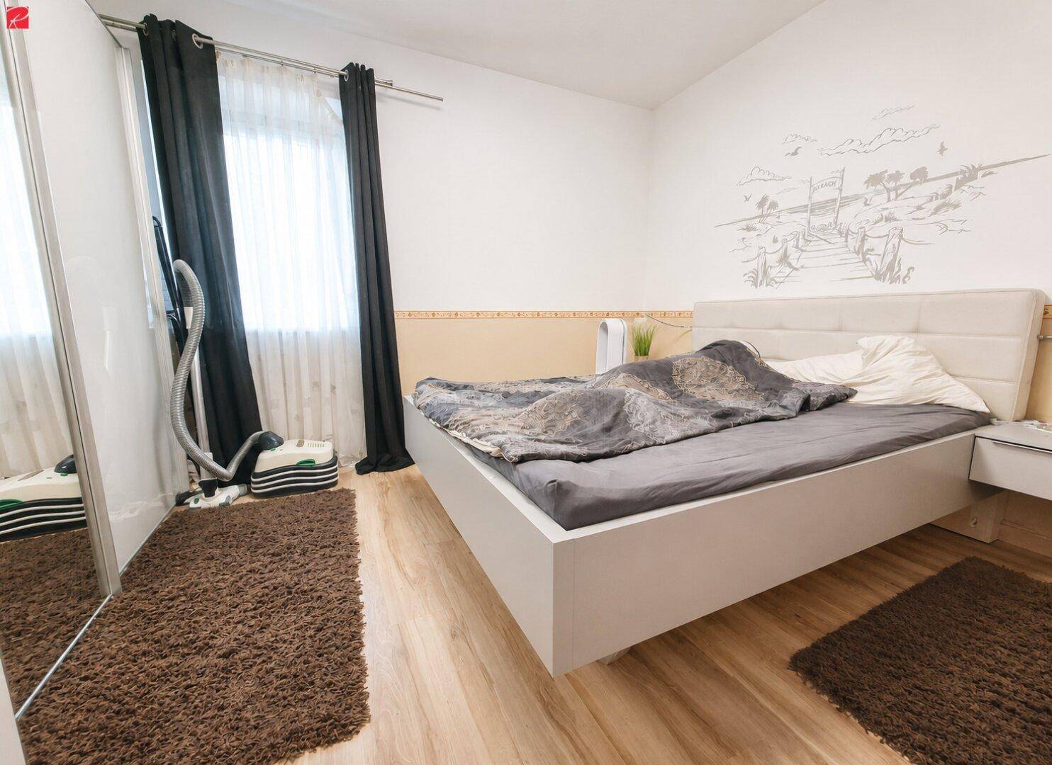 Helles Schlafzimmer mit modernem Bett, Spiegelschrank und warmem Holzboden.