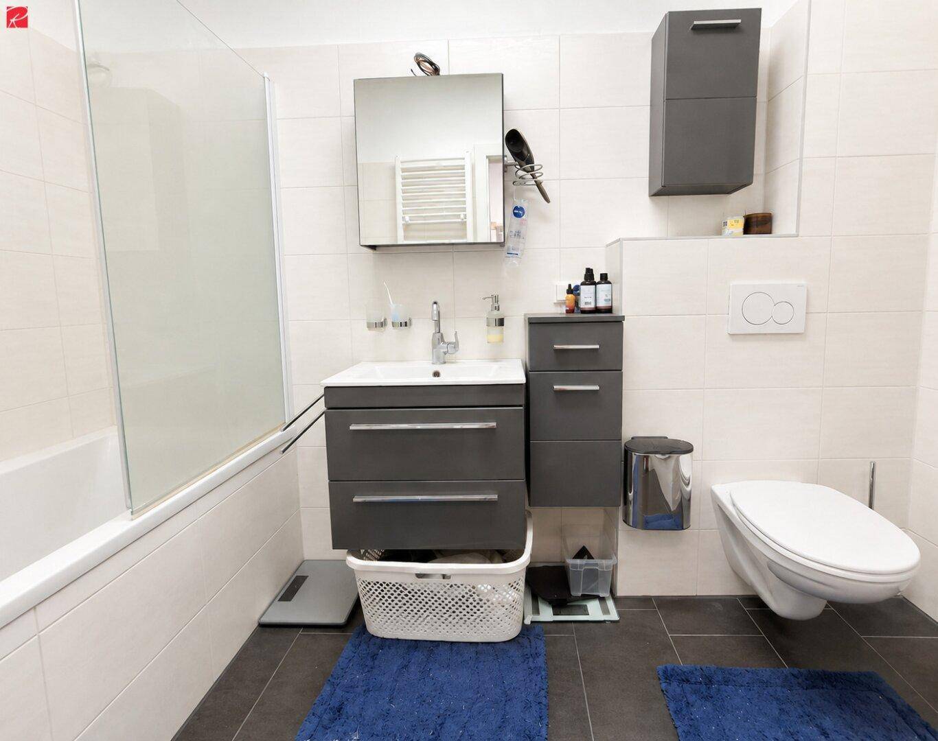 Modernes Badezimmer mit Badewanne, wandhängendem WC, Waschtisch und Spiegelschrank.
