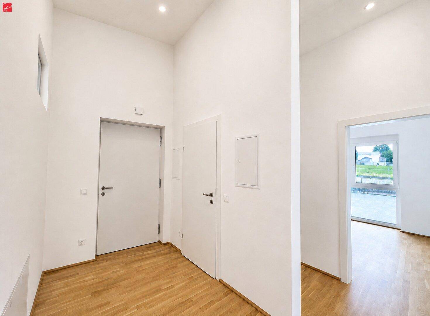 Geräumiger Flur mit Holzparkettboden, weißen Wänden und modernen Türen, der zu weiteren Räumen führt.