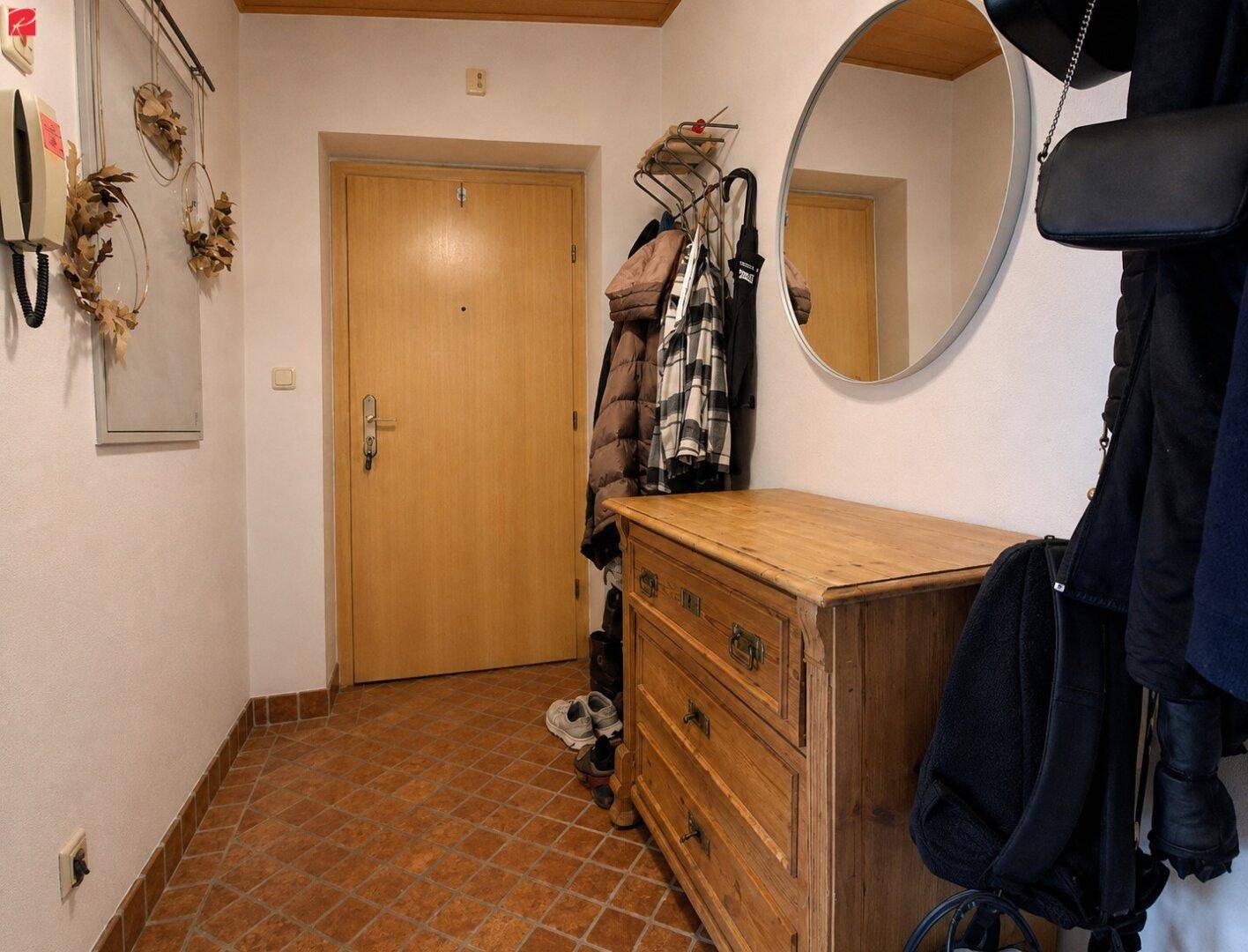 Eingangsbereich mit rustikaler Holzkommode, Spiegel und Terrakotta-Fliesenboden für einen warmen Empfang.