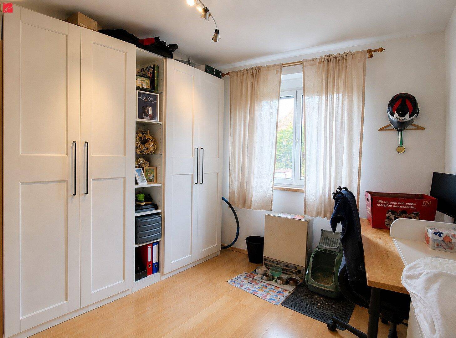 Helles Schlafzimmer mit großen weißen Kleiderschränken, Schreibtisch und Fenster mit Holzboden.