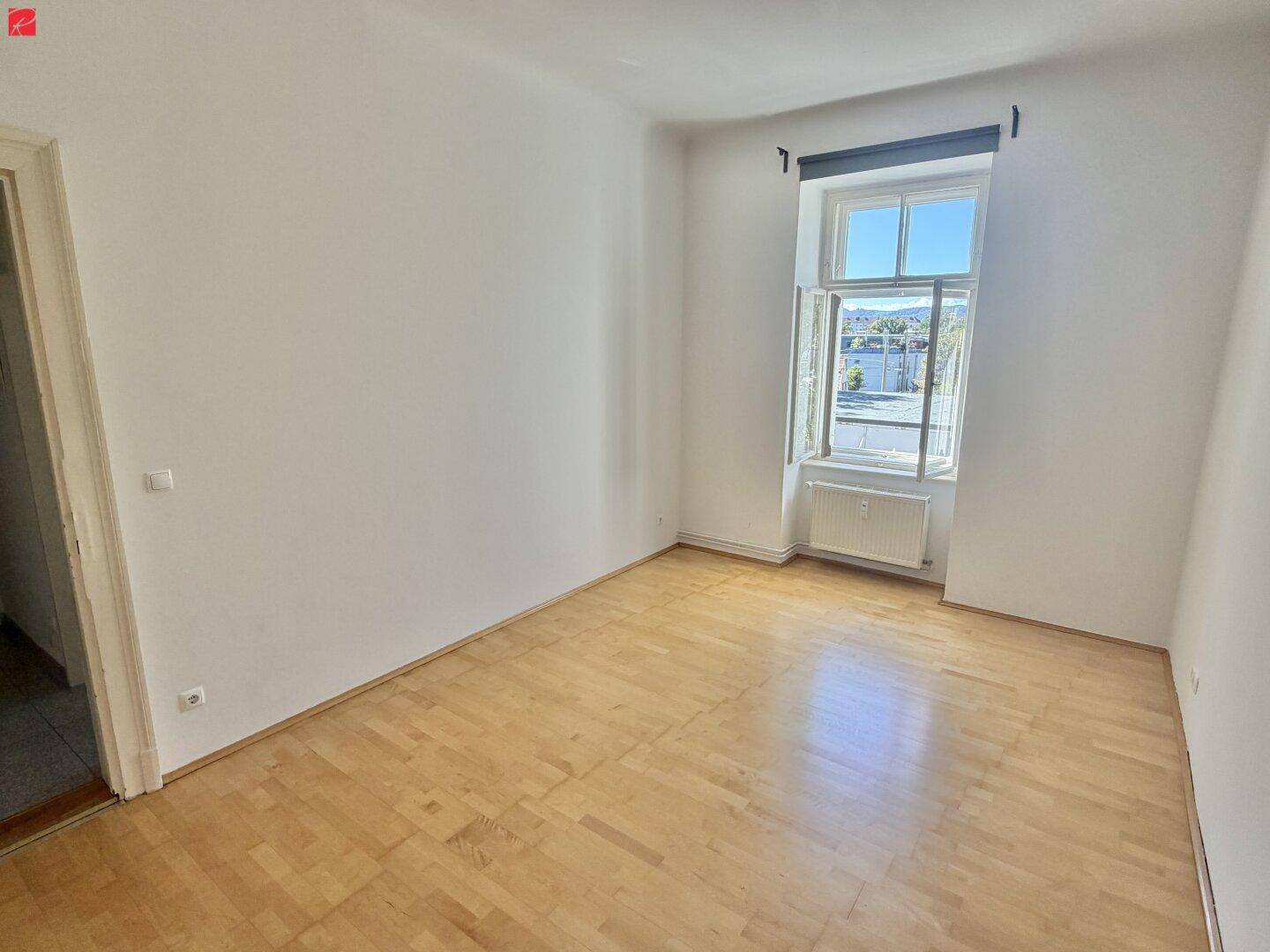 Geräumiges Schlafzimmer mit Laminatboden und einem Fenster, das viel Tageslicht hereinlässt.