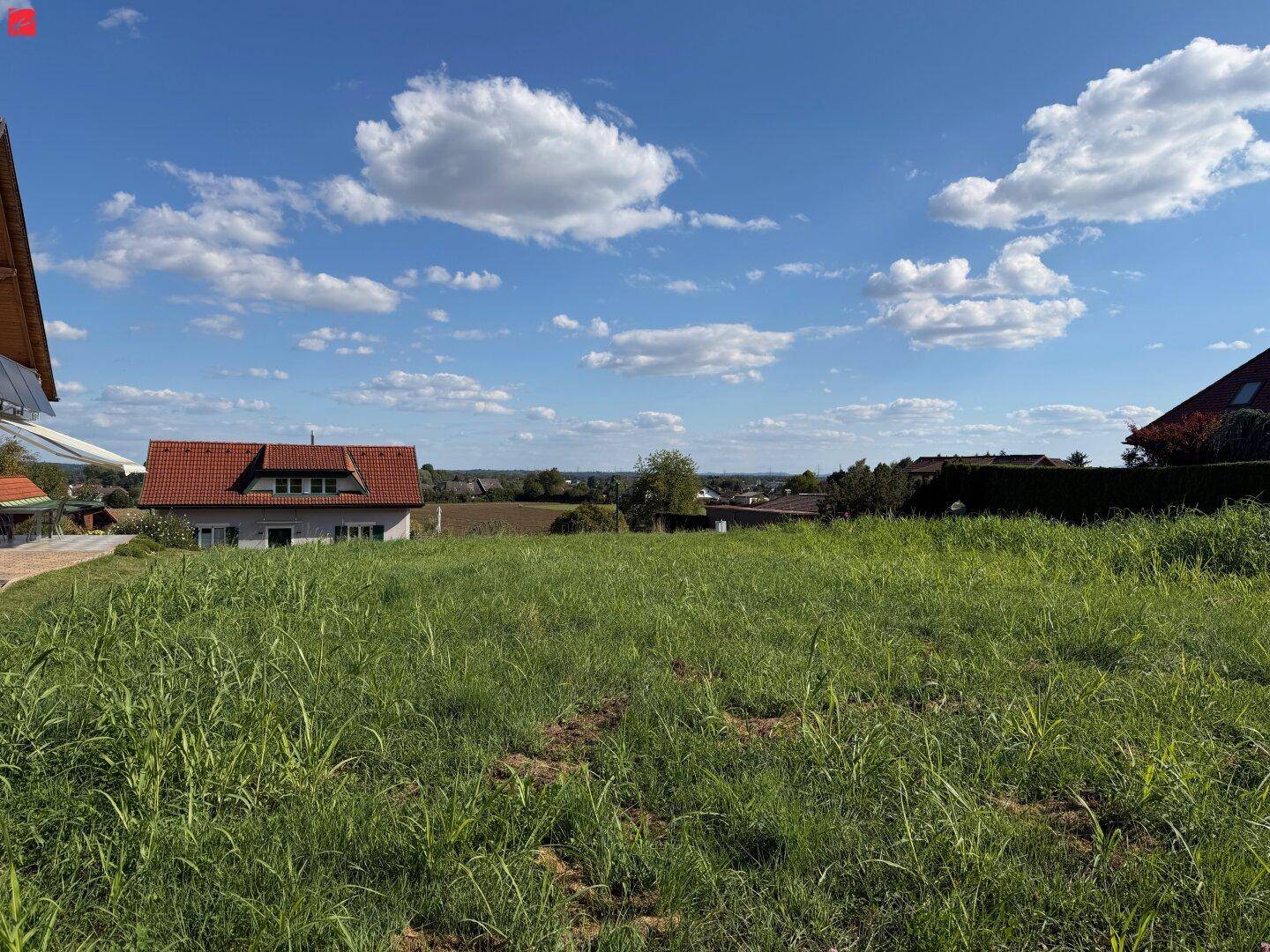 Weitläufiges Grundstück mit grüner Wiese und Blick auf die umliegende Landschaft und Häuser.