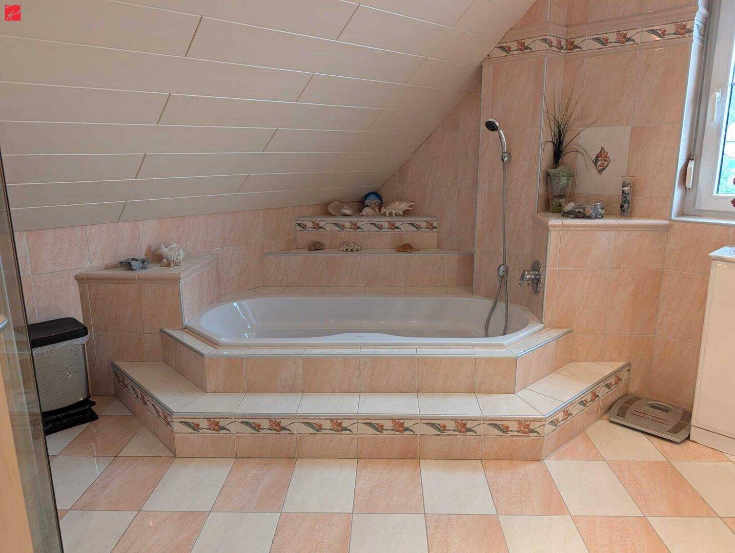 Badezimmer im Dachgeschoss mit eingebauter Badewanne und verspielten Fliesenmustern.