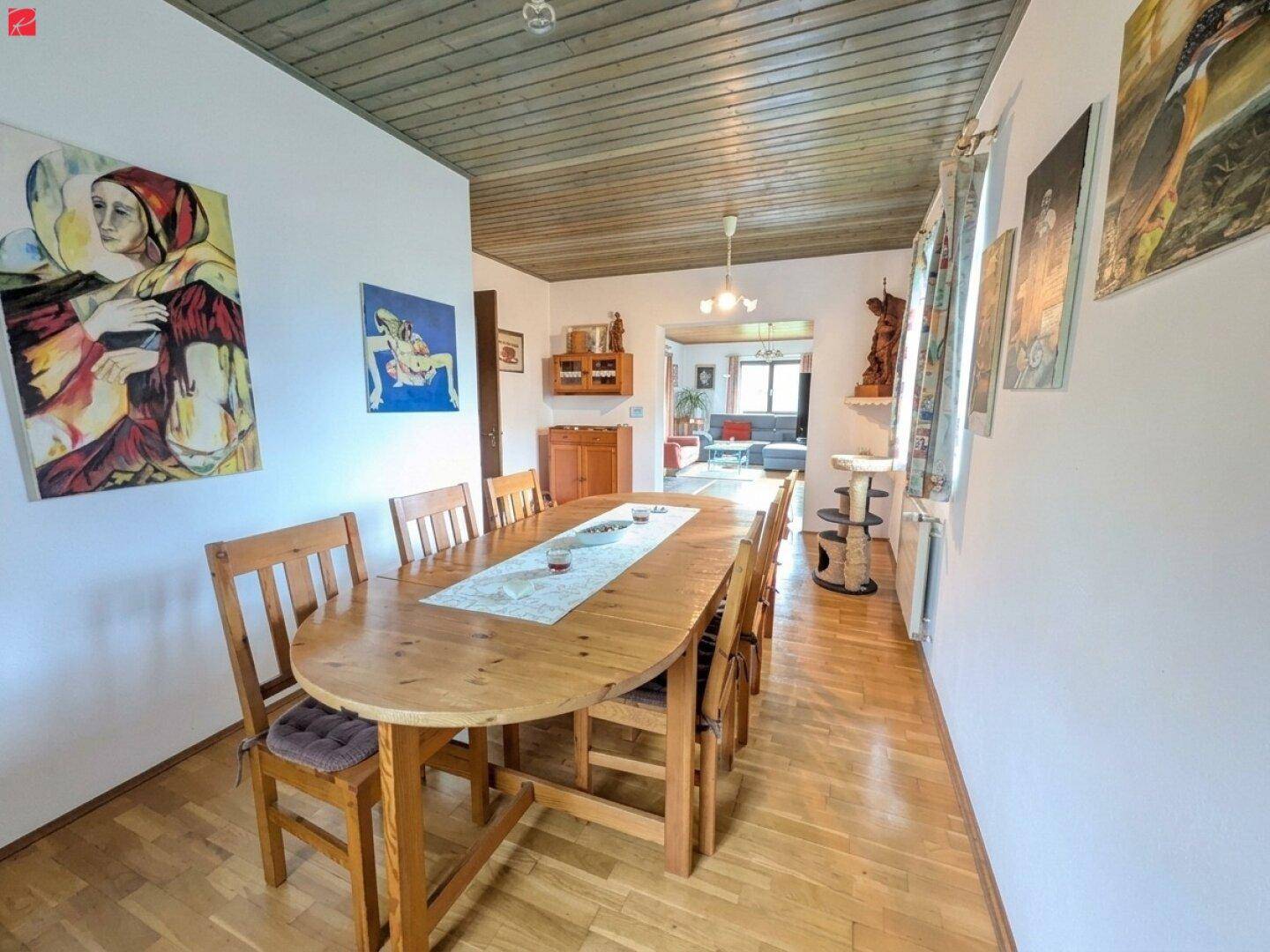 Heller Essbereich mit großem Holztisch, passenden Stühlen und Holzpaneeldecke für gesellige Runden.