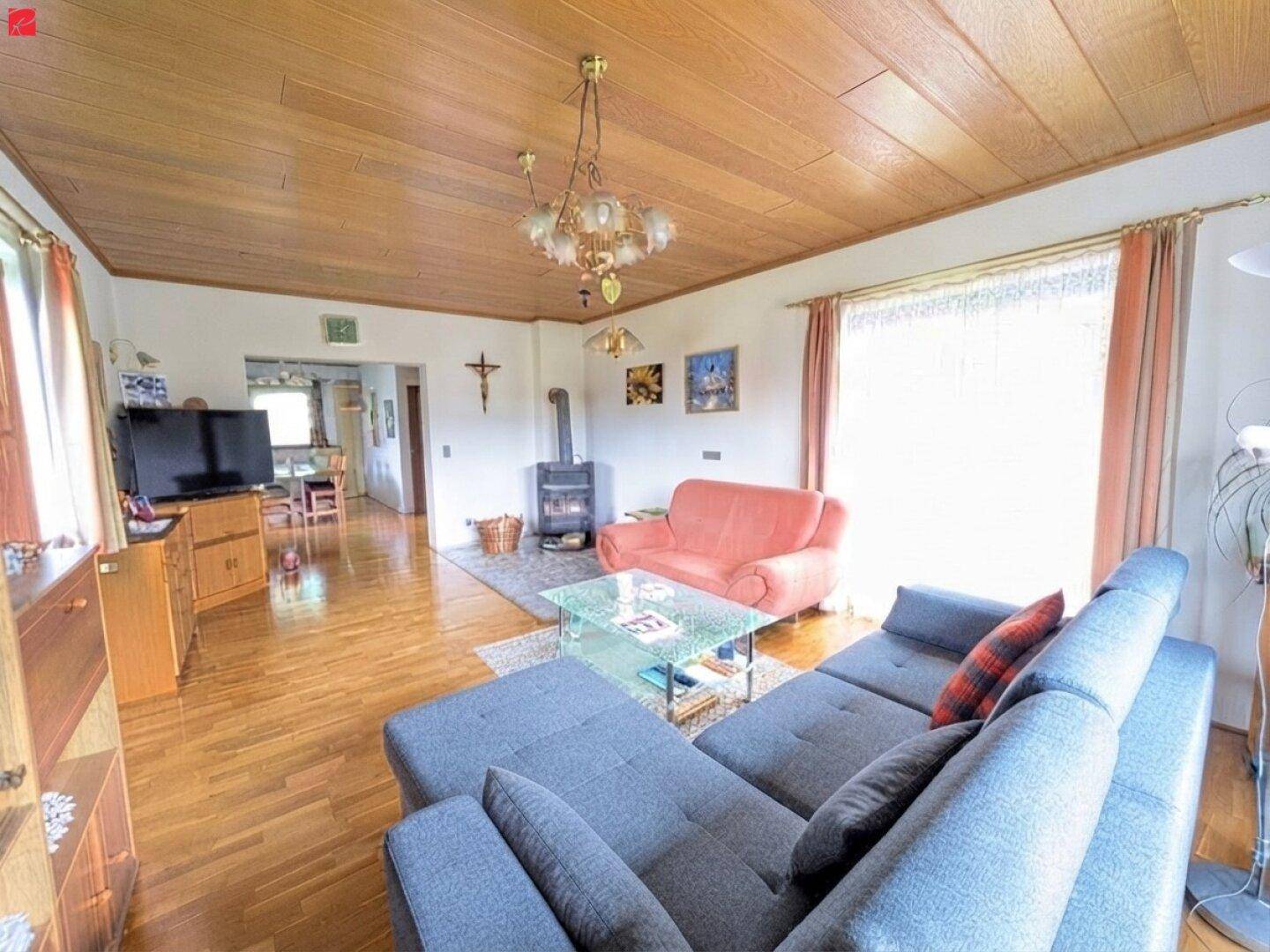 Gemütliches Wohnzimmer mit Holzpaneeldecke, Parkettboden und einem Kaminofen für behagliche Wärme.