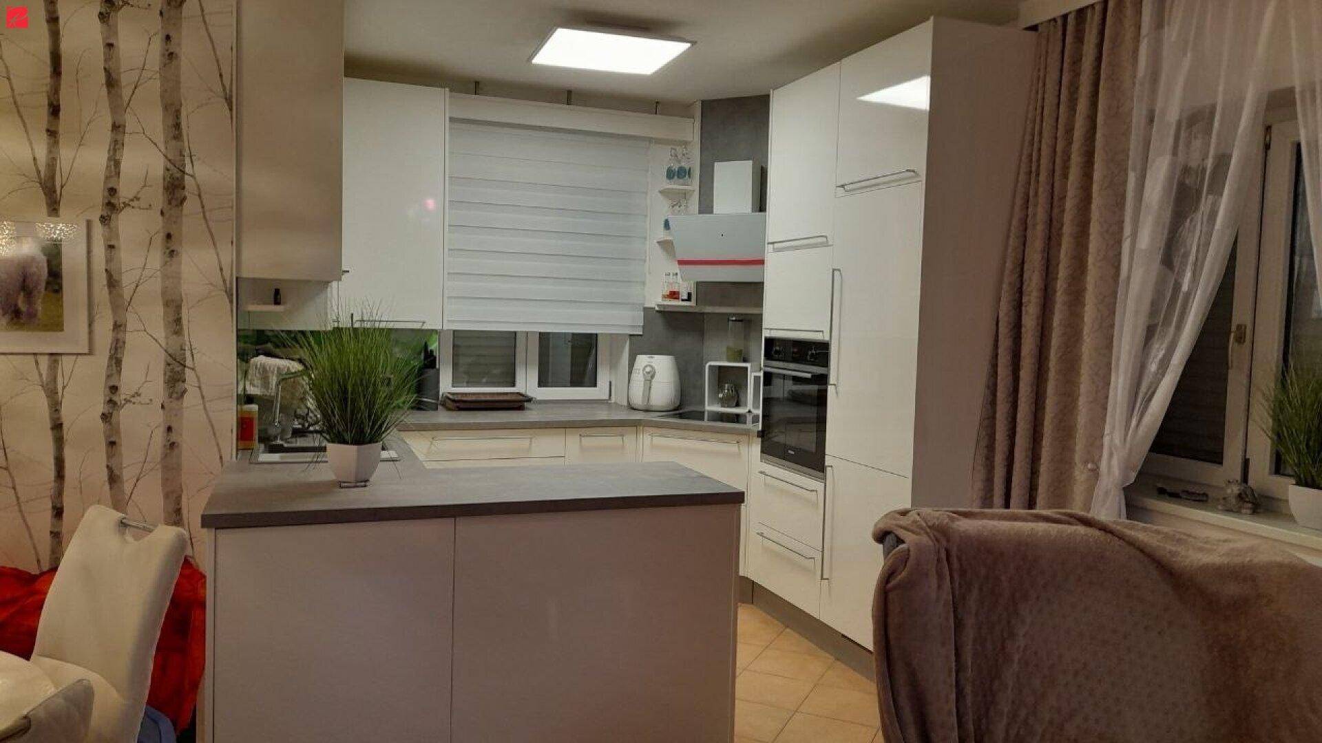 Moderne Küche mit weißen Schränken, integrierten Geräten und Arbeitsinsel.