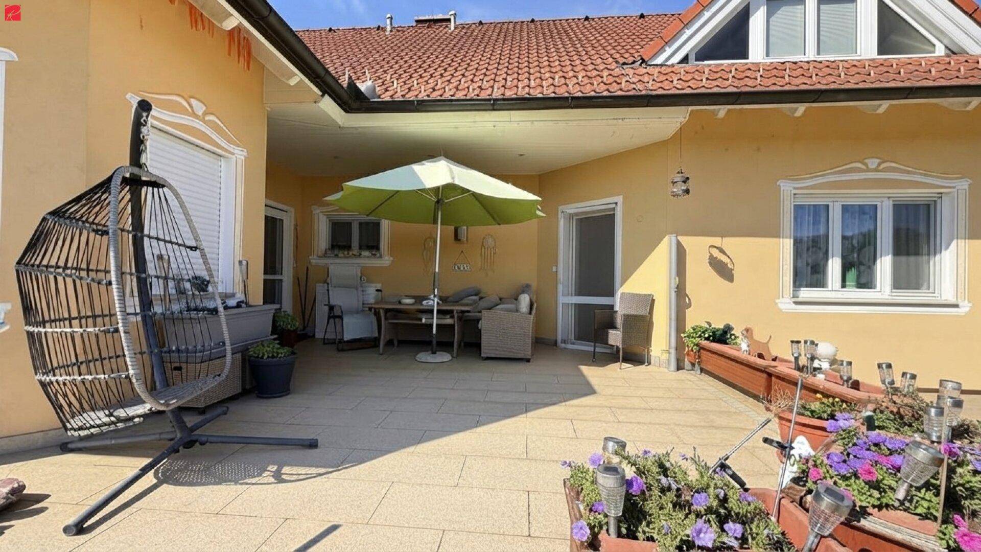 Sonnige Terrasse mit bequemen Gartenmöbeln, Sonnenschirm und Blumenkästen.