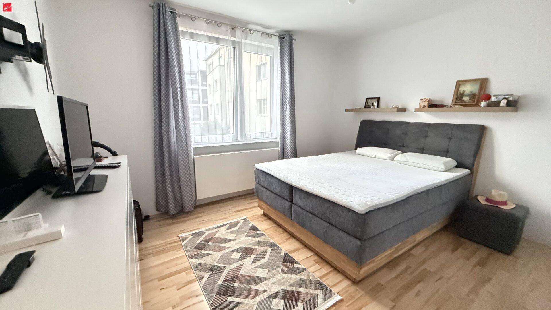 Schlafzimmer mit Doppelbett, Holzboden und großem Fenster für viel Tageslicht.