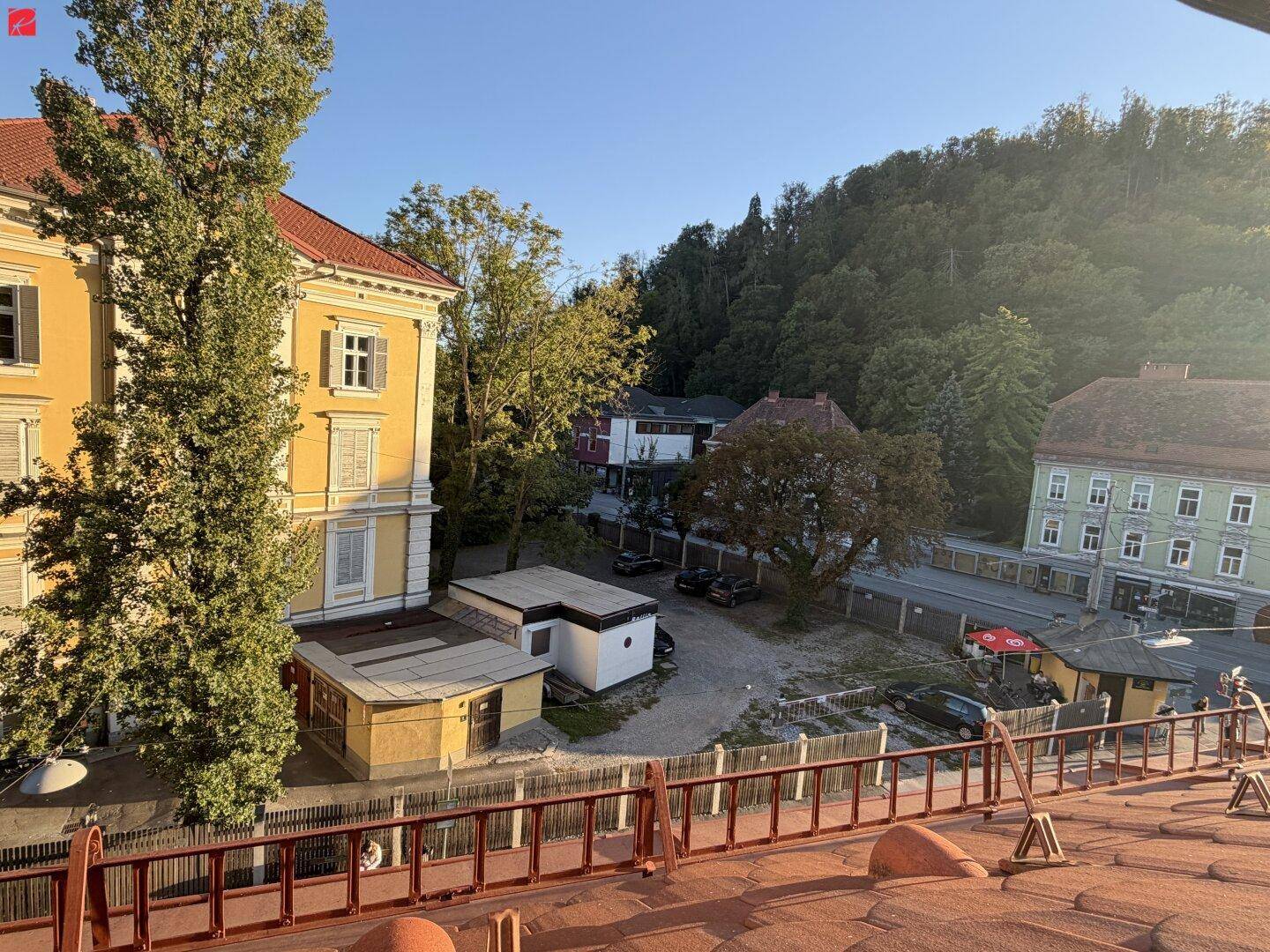 Blick auf die umliegenden Gebäude und bewaldete Hügel in der Ferne an einem sonnigen Tag.