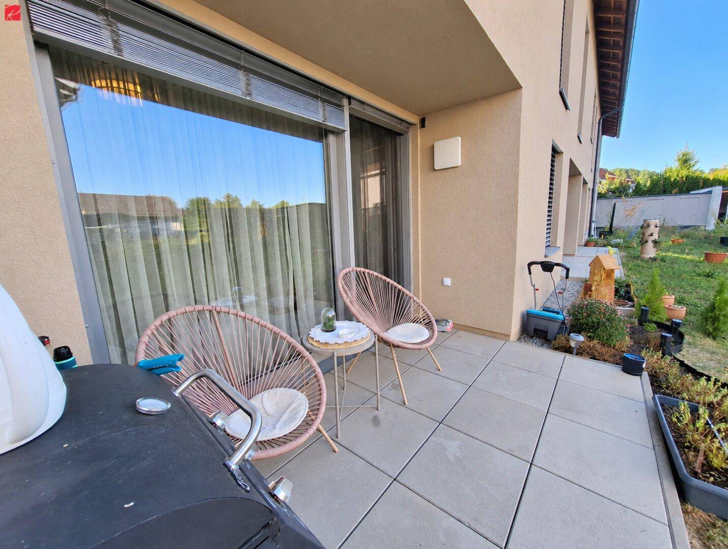 Sonniger Terrassenbereich mit Sitzgelegenheiten und Grill, ideal für entspannte Stunden im Freien.