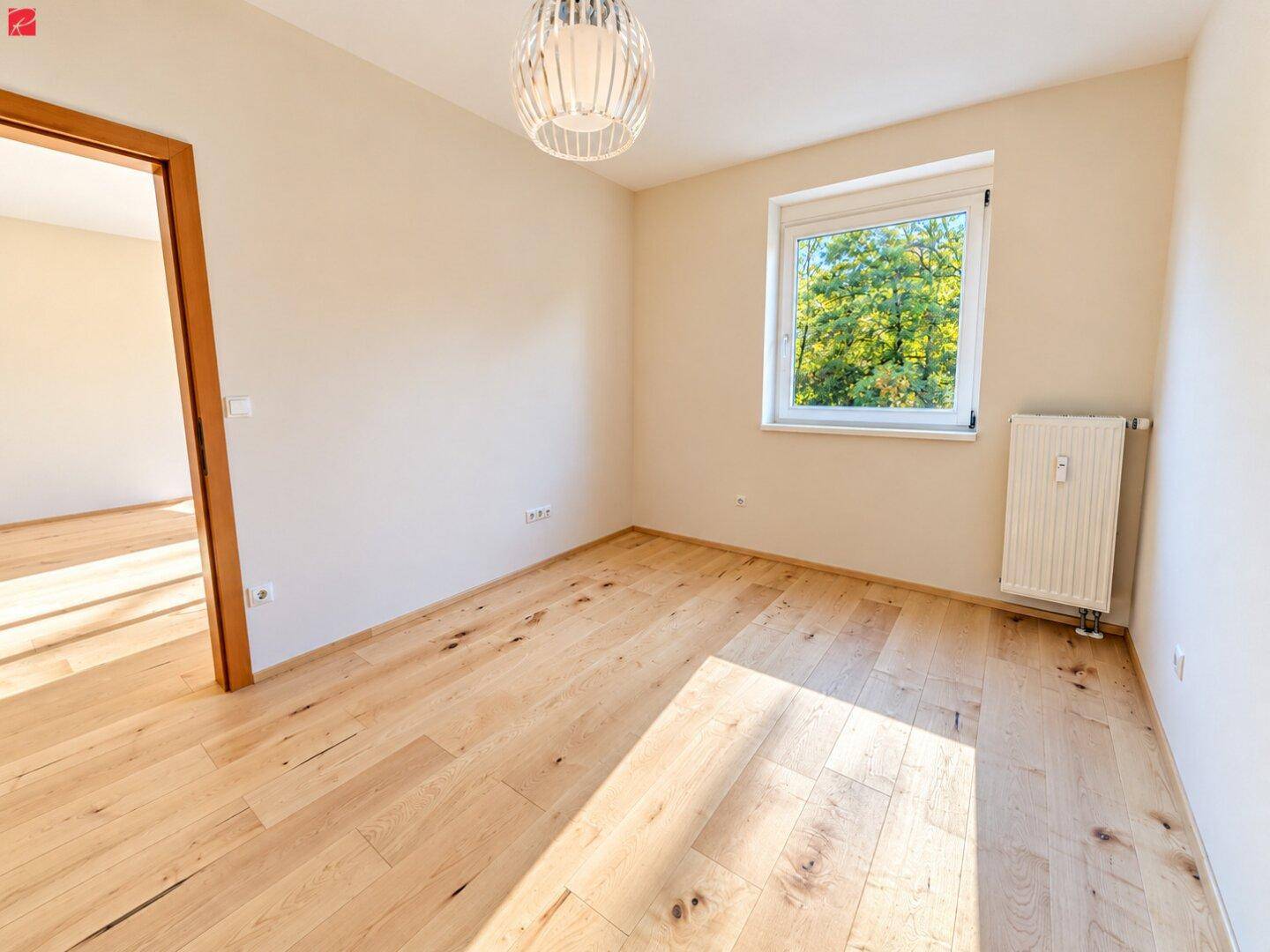 Gemütliches Schlafzimmer mit Holzboden und Fenster, das einen schönen Blick ins Grüne bietet.