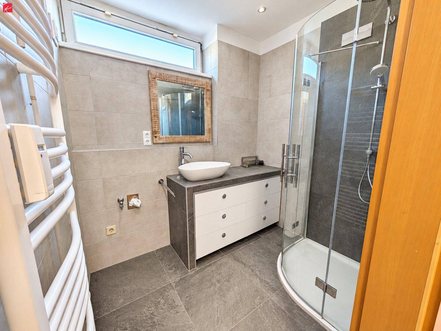 Modernes Badezimmer mit begehbarer Dusche, Einzelwaschbecken und beheiztem Handtuchhalter.