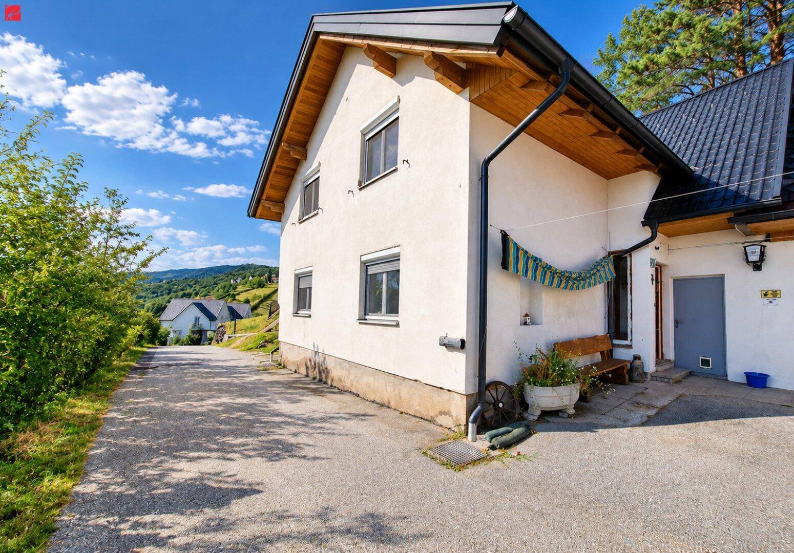 Seitenansicht des Hauses mit weißer Fassade, dunklem Dach und gepflegter Umgebung.