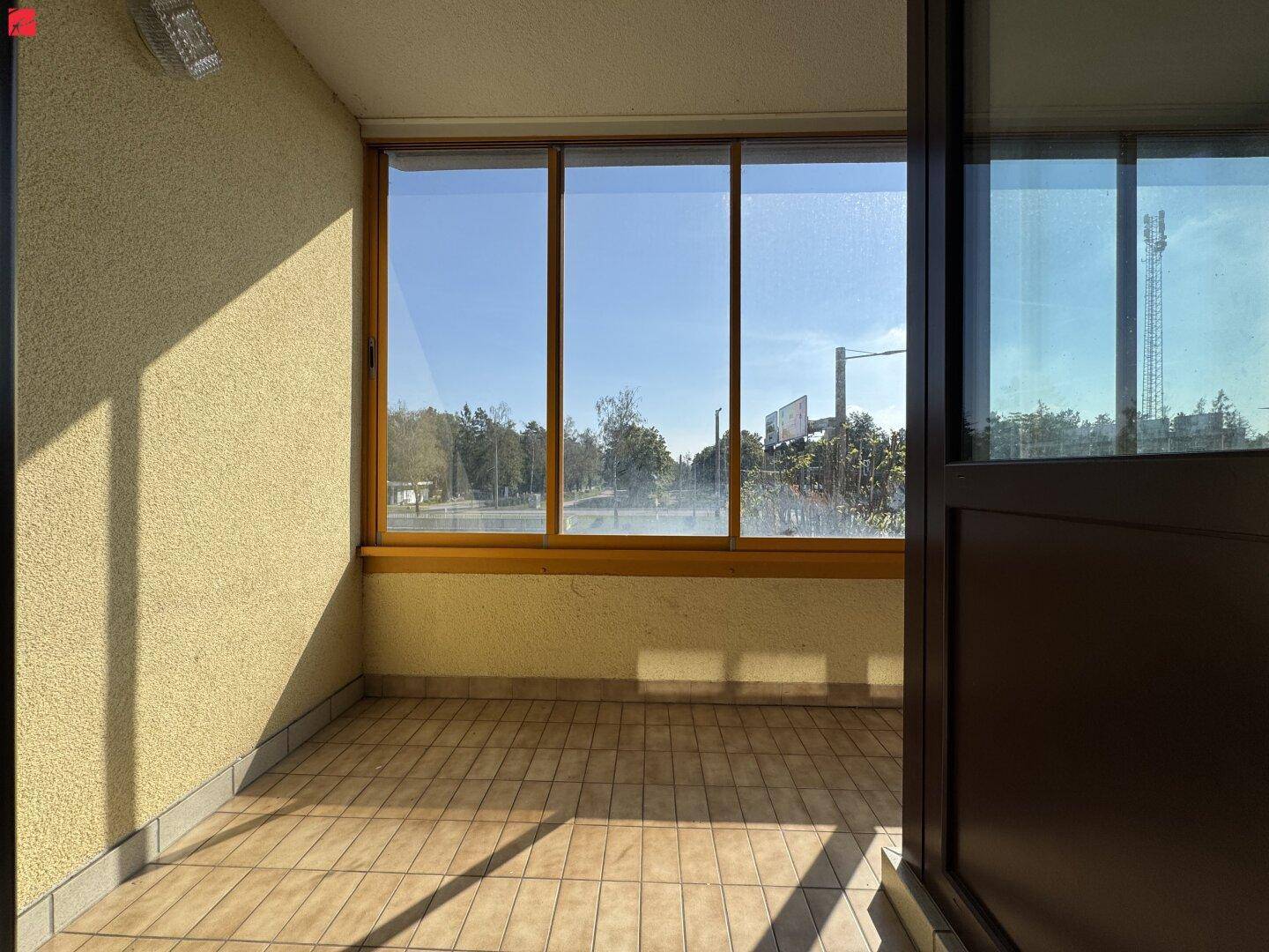 Verglaste Loggia mit Fliesenboden und weitem Blick ins Grüne, perfekt für entspannte Stunden im Freien.