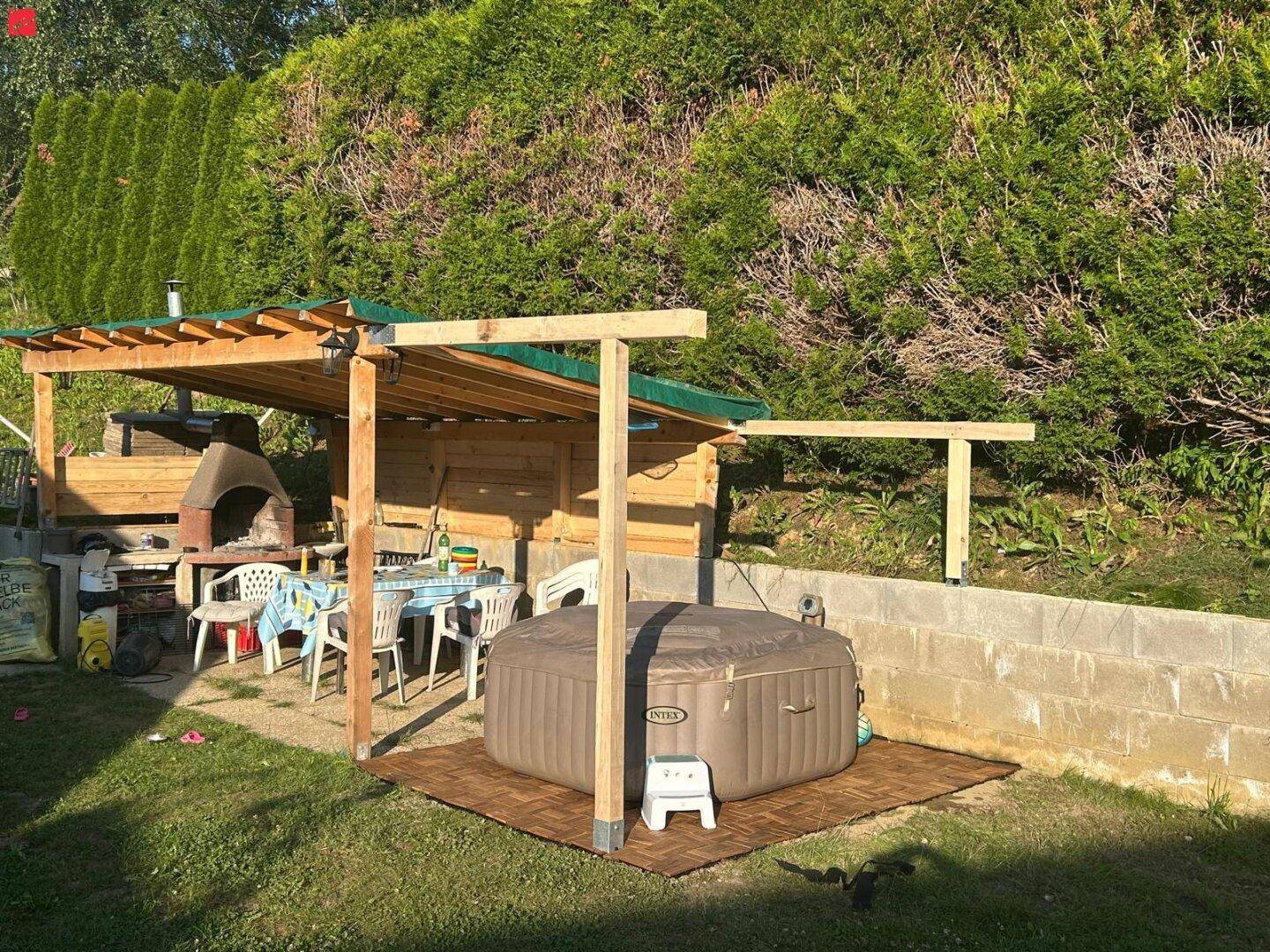 Großer Gartenbereich mit überdachtem Grillplatz, Pizzaofen und aufblasbarem Whirlpool.