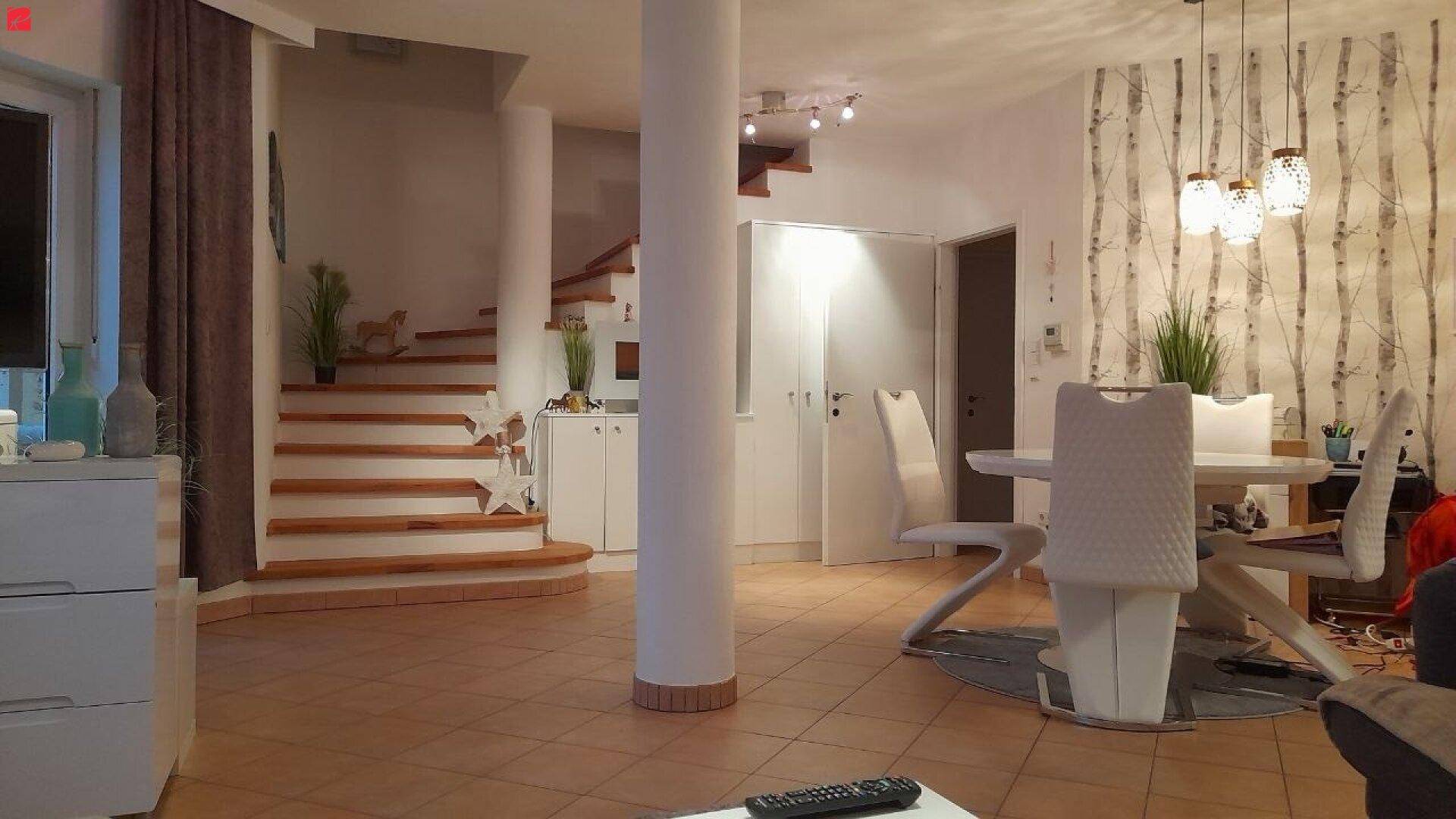 Geräumiger Wohn- und Essbereich mit offener Treppe und heller Fliesenboden.