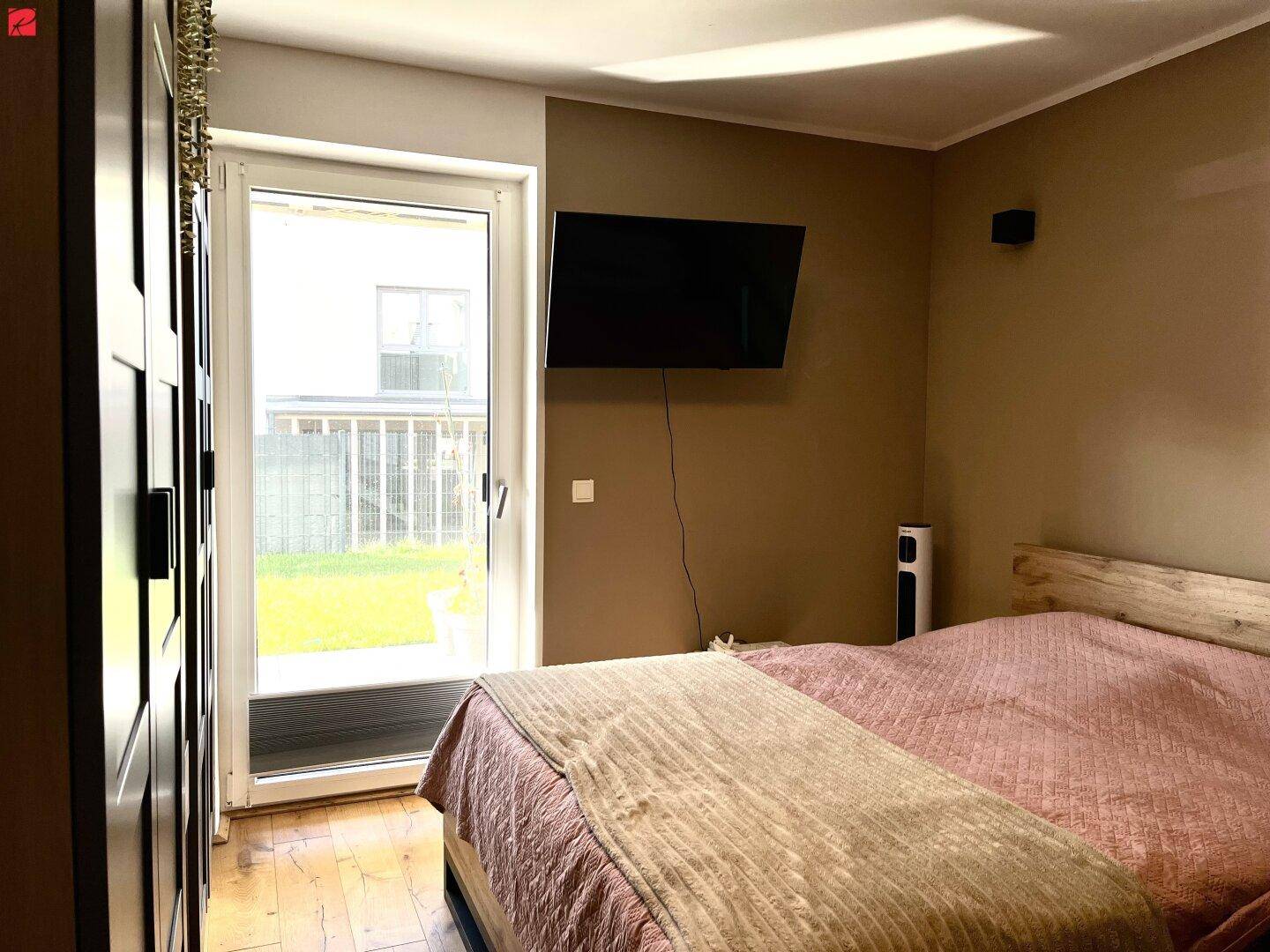 Schlafzimmer mit Holzboden, großem Kleiderschrank und direktem Zugang zum Garten.