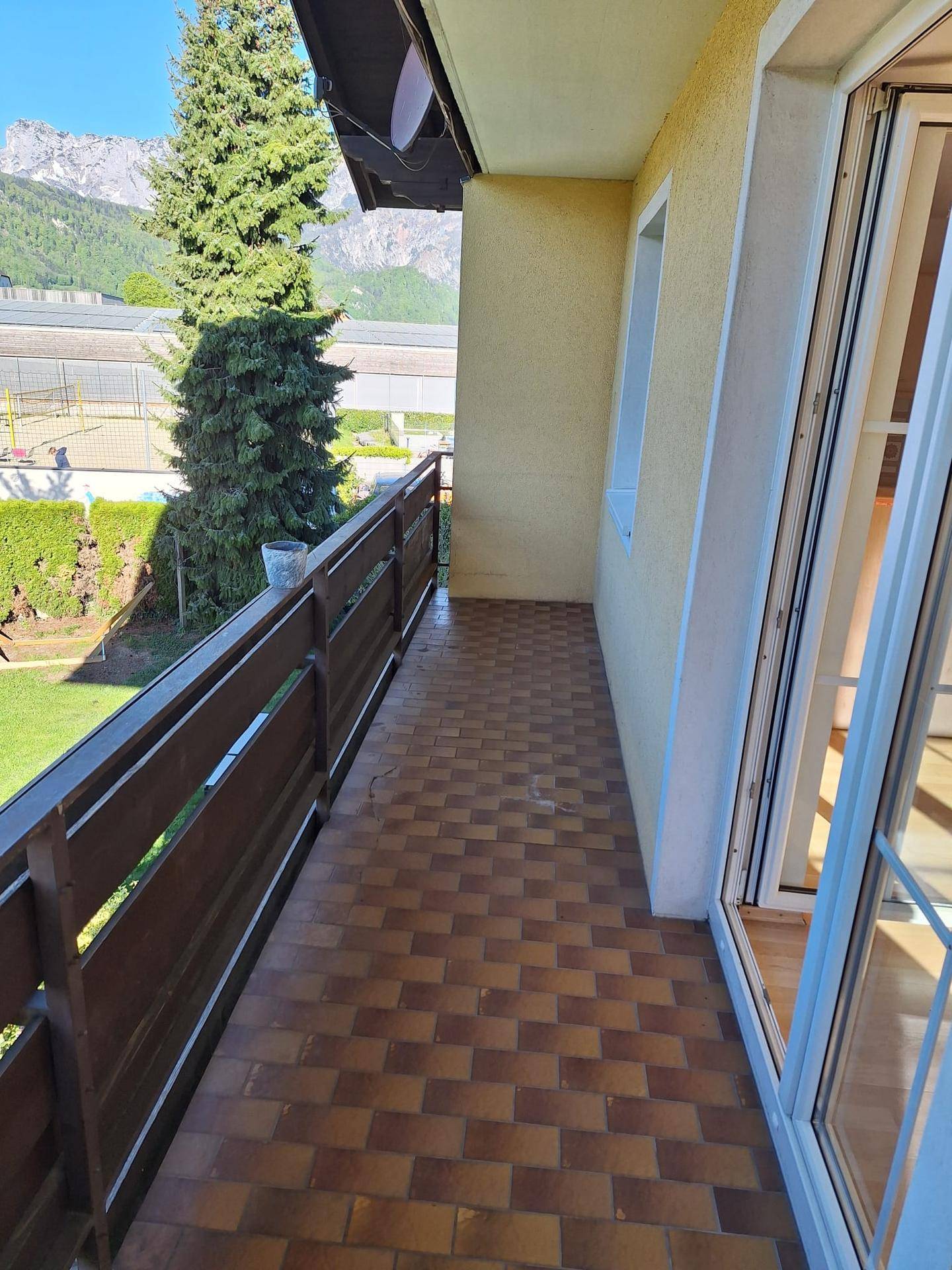Langer Balkon mit Fliesenboden, Holzgeländer und herrlichem Bergblick.