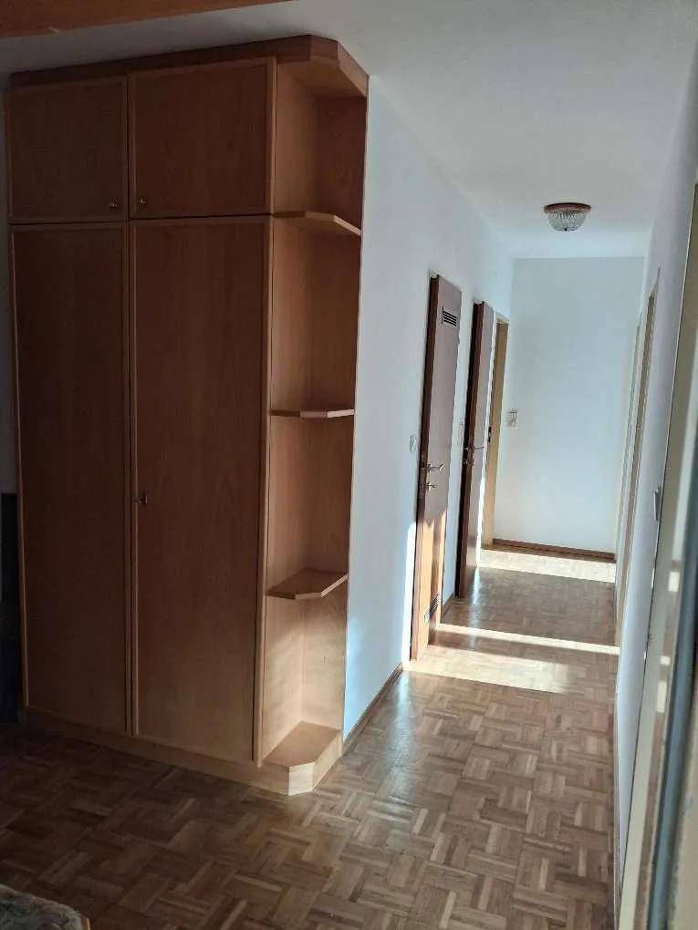 Heller Flur mit Fischgrätparkett und einem großen, integrierten Einbauschrank aus hellem Holz.