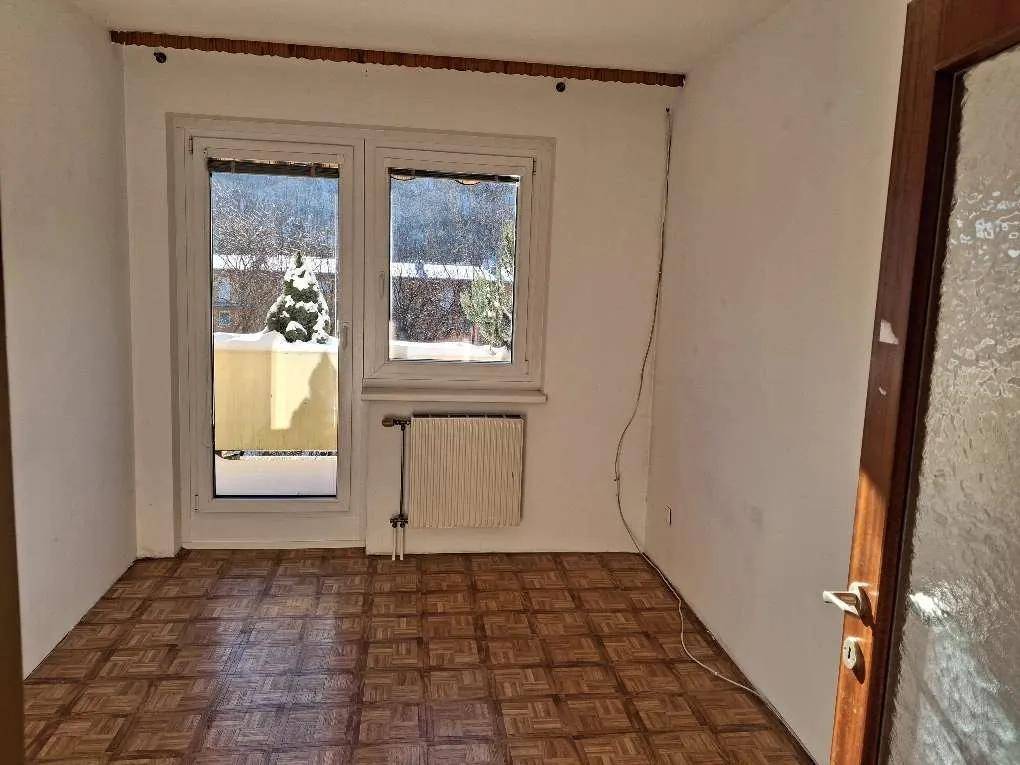 Helles Zimmer mit Fischgrätparkett und Balkonzugang, bietet einen angenehmen Blick ins Grüne.