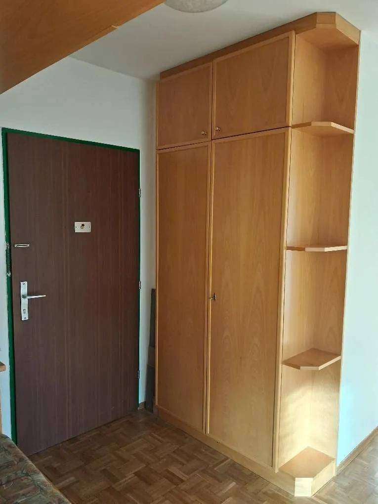 Eingangsbereich mit großem Holzeinbauschrank und einer dunklen Eingangstür, die zum Wohnbereich führt.