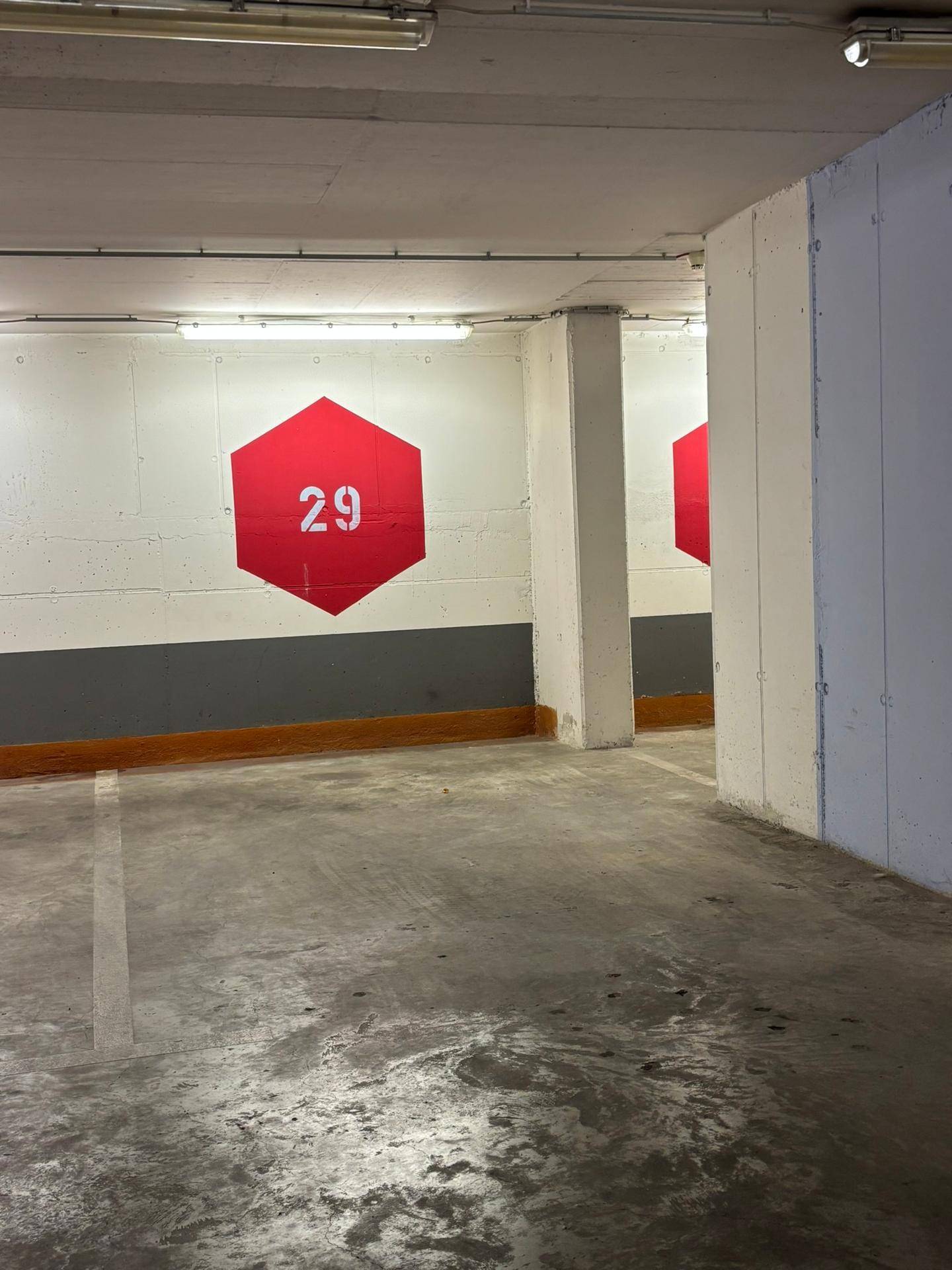 Saubere Tiefgarage mit Betonoberflächen, nummerierten Parkplätzen und einfacher Beleuchtung.