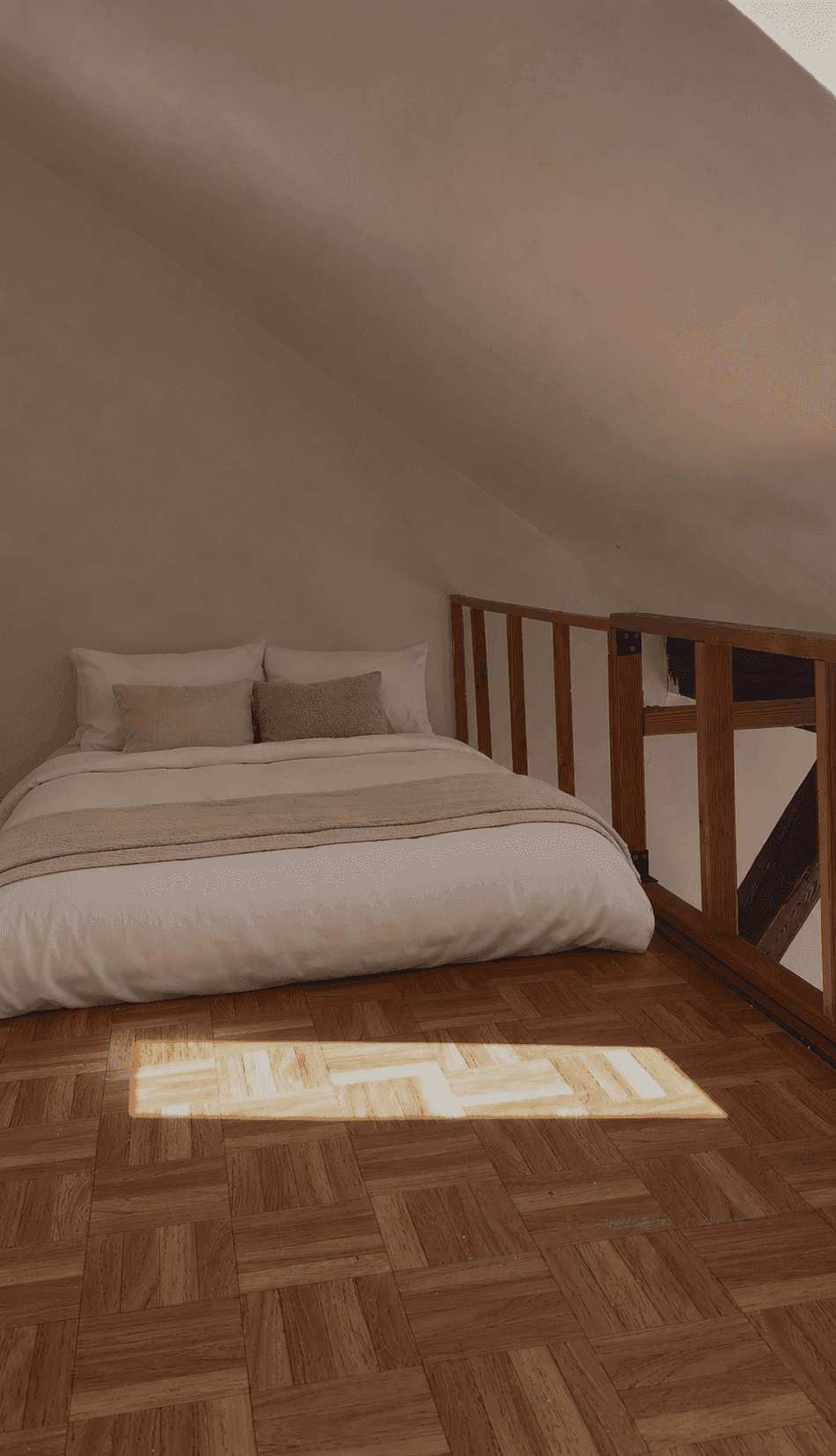 Gemütliches Schlafzimmer auf einer Empore mit Dachschräge, Holzboden und natürlichem Lichteinfall.