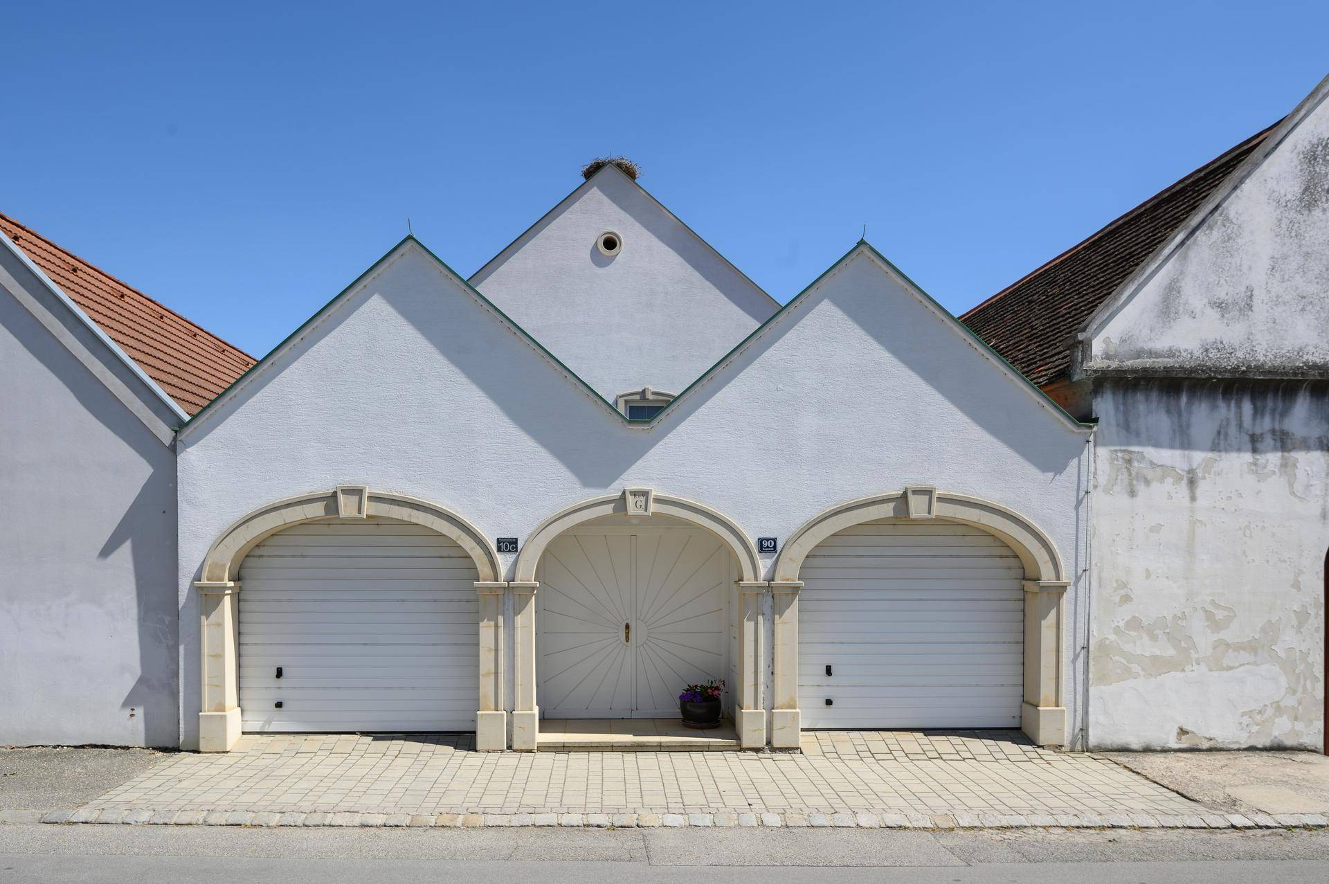 Historische Fassade mit drei Bögen, zwei Garagentoren und einem zentralen Eingang, in traditionellem Stil.