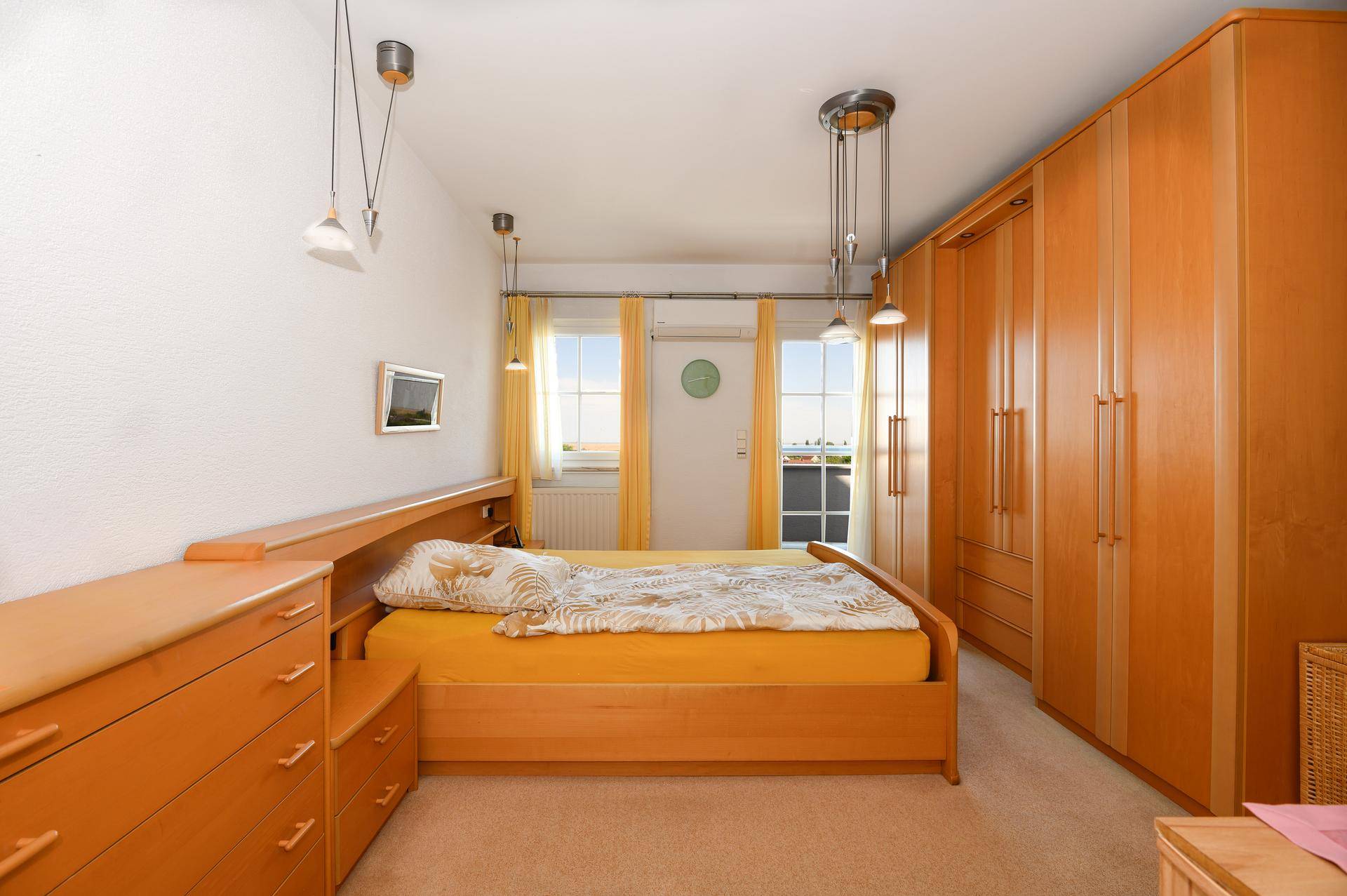 Gemütliches Schlafzimmer mit Holzmöbeln, Teppichboden und gelben Vorhängen, die für eine warme Atmosphäre sorgen.