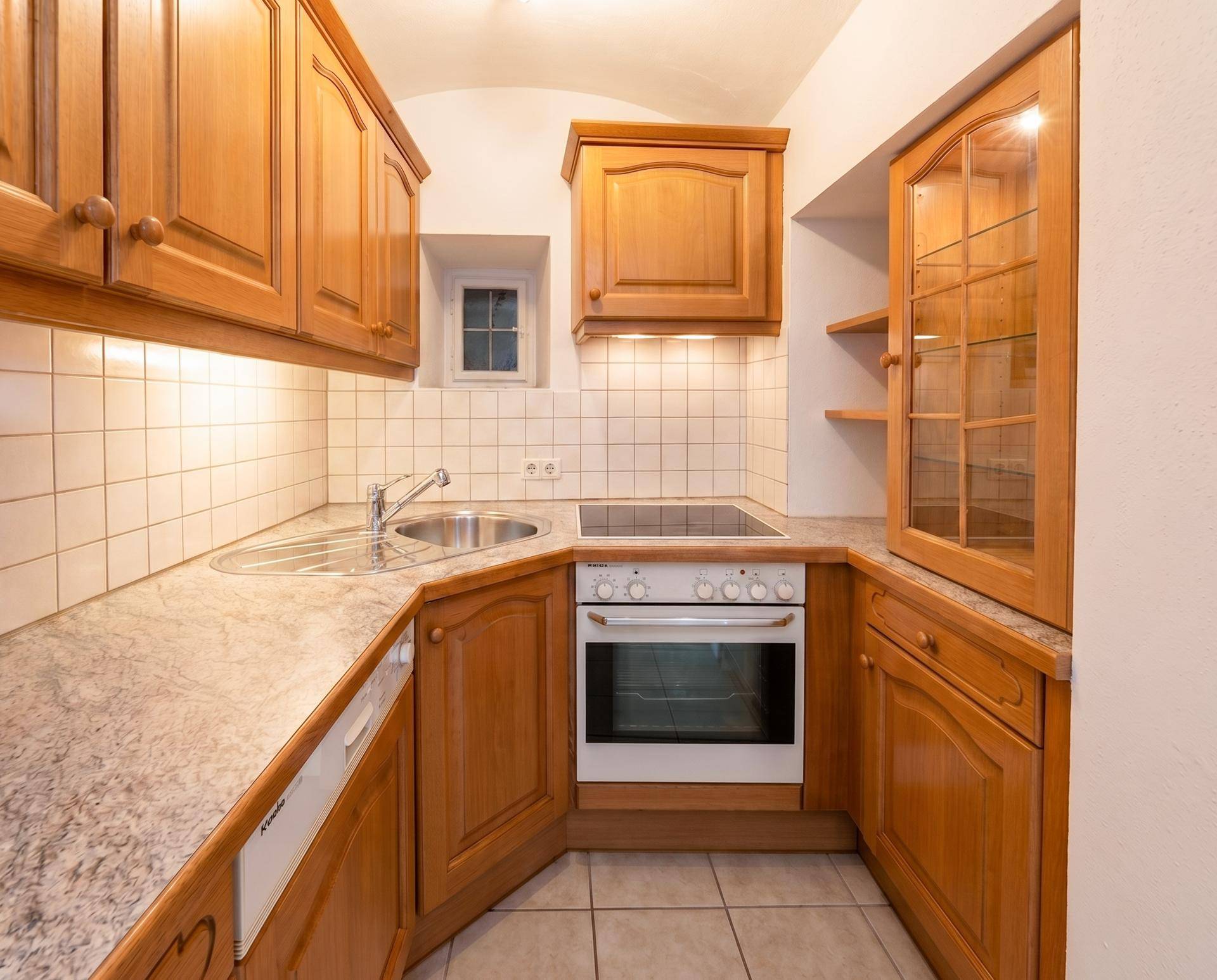 Kleine, funktionale Küche mit Holzschränken, integriertem Backofen und Kochfeld, ideal für den täglichen Gebrauch.