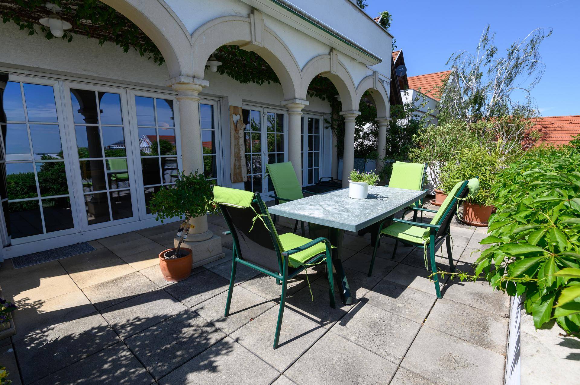 Große Terrasse mit Sitzgelegenheiten und Zugang zum Haus durch elegante Fenstertüren, mit Weitblick.