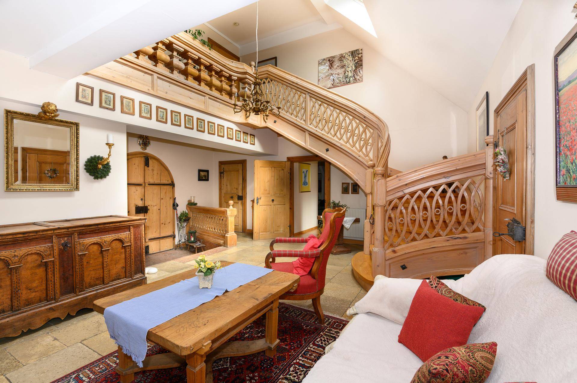 Traditioneller Wohnbereich mit beeindruckender Holztreppe, Steinfliesenboden und rustikalen Möbeln.