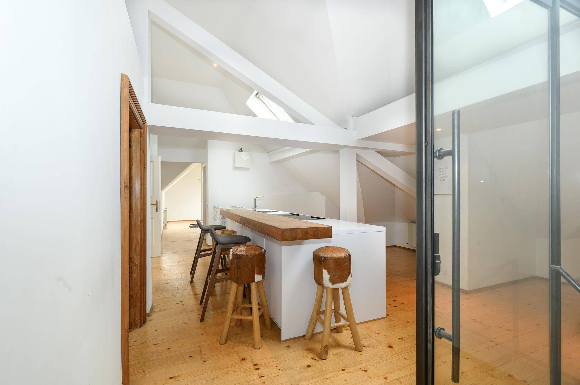 Helle Küchenzeile im Dachgeschoss mit Holzboden, Barhockern und moderner Ausstattung.