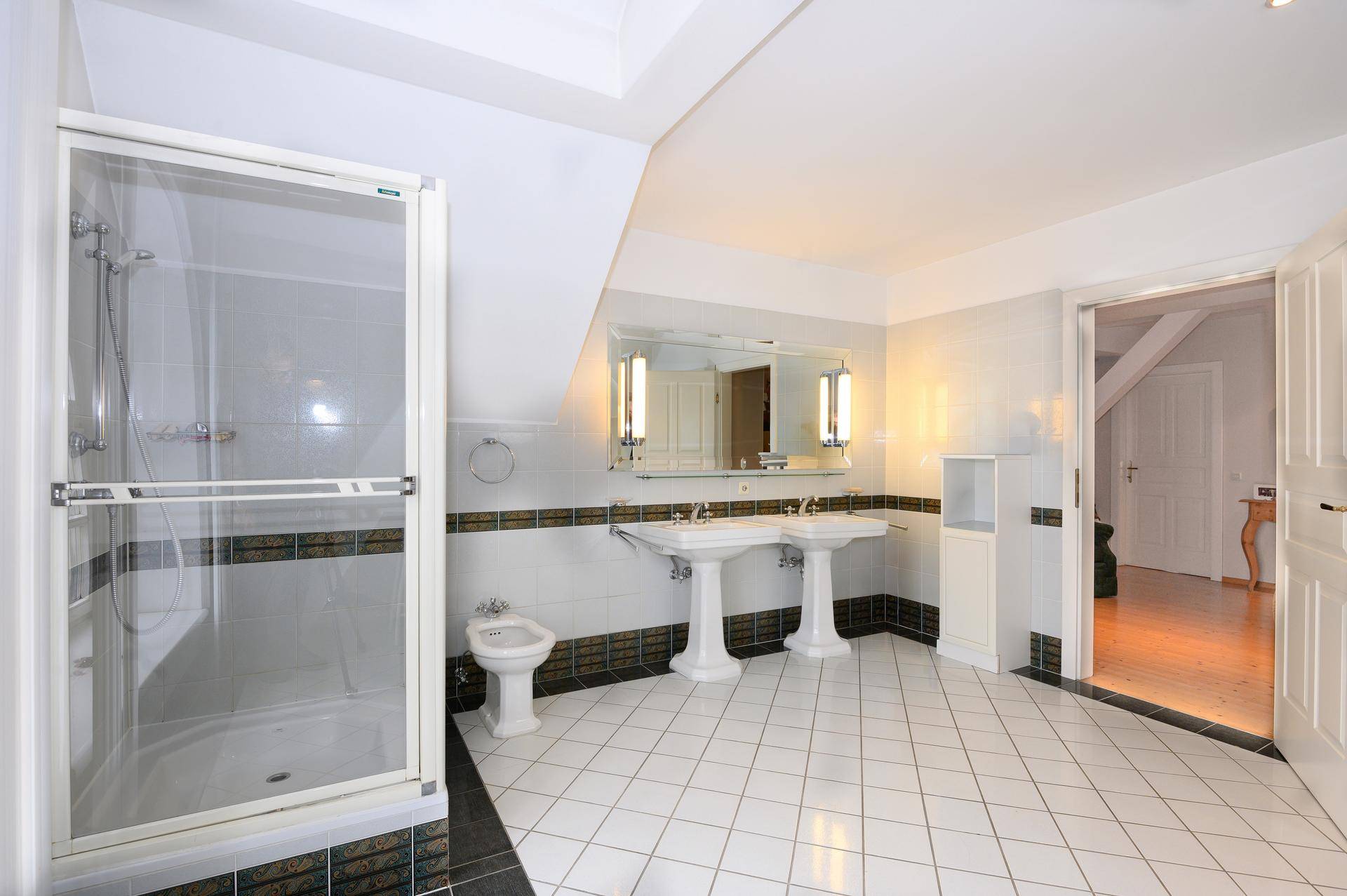 Geräumiges Badezimmer mit zwei Waschbecken, Duschkabine und Fliesenboden.