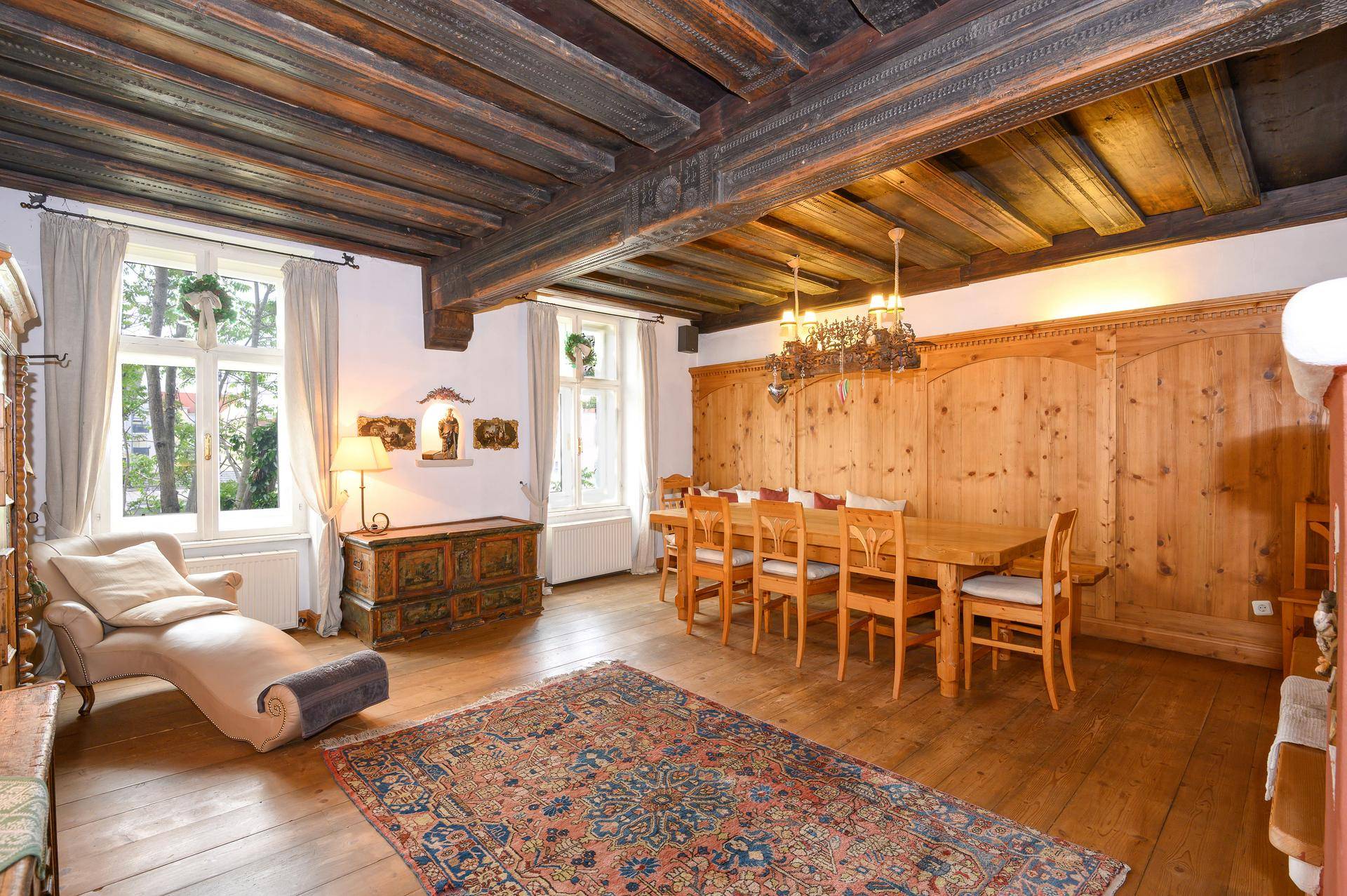 Elegantes Esszimmer mit Holzbalkendecke, Holzdielenboden und großem Esstisch.